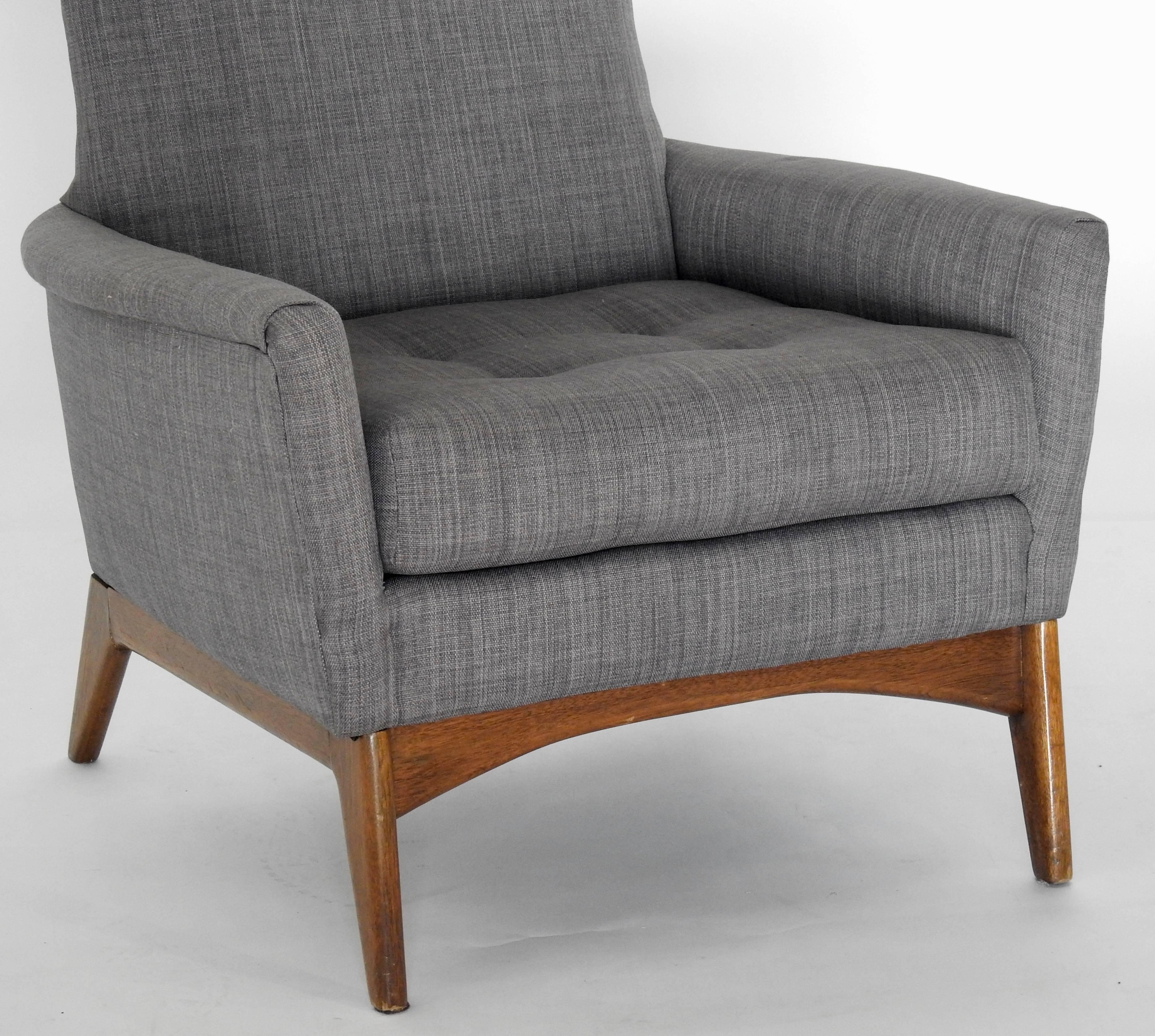 A mid-century high-back armchair by Adrian Pearsall. The chair has an angular form with a buttoned back and loose seat cushion. It is upholstered in a blue denim colored linen fabric. The walnut base features angled feet. Adrian Pearsall (1925-2011)