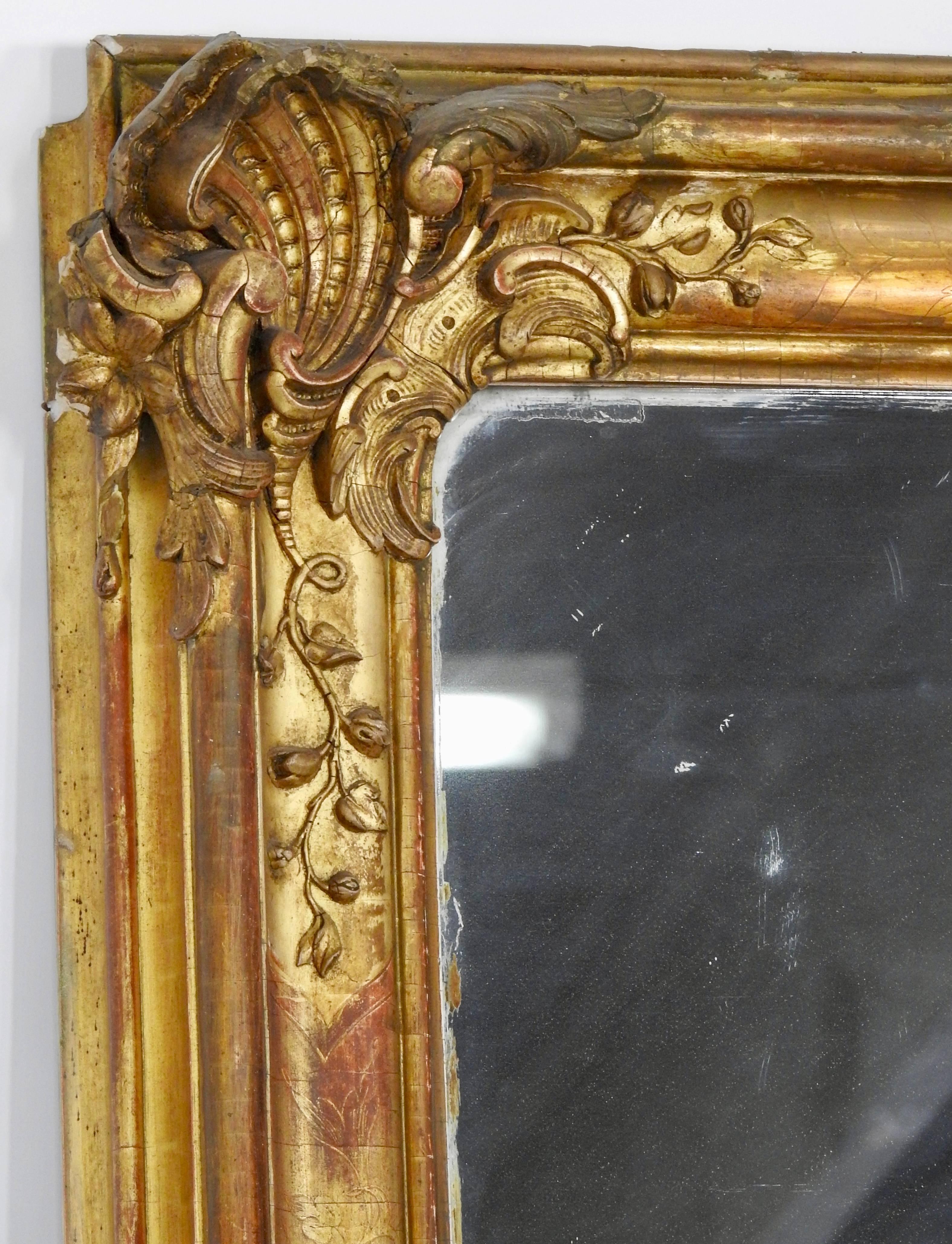 Up for your consideration is a 19th century gilded wood mirror from France. Detailed vines with floral and scroll embellishments accent this lovely mirror. The gilt work is over a finely done gesso and rabbit skin glue giving it that warm glow. Aged