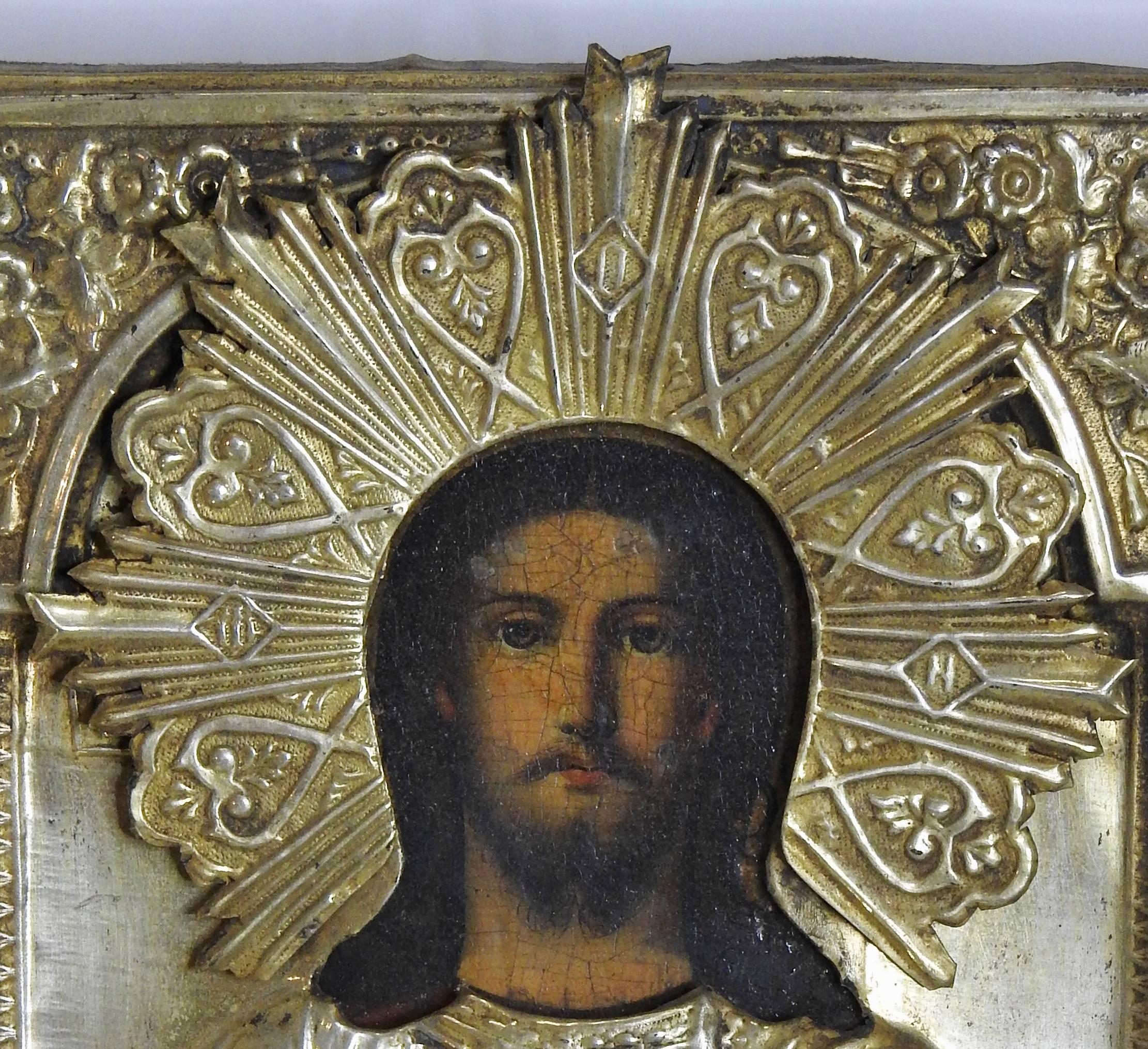 Soft hand rubbed gold graces this early 19th century Russian icon made of embossed bronze. The detail work is exquisite. The metal is pierced to accent the painting of Christ which is hand-painted oil on canvas with a crackle finish from age. An
