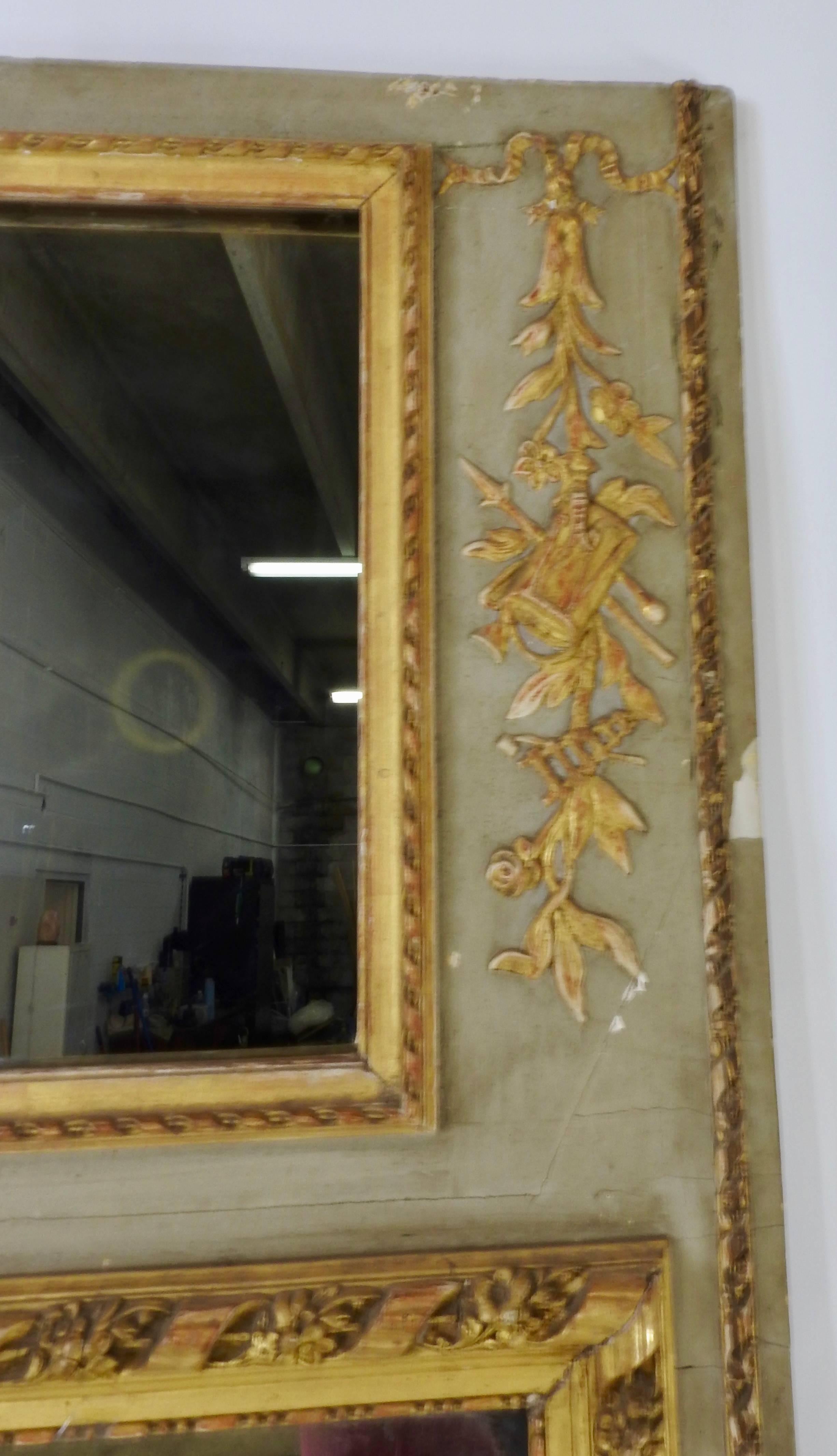 During the 19th century, this gorgeous Rococo Trumeau mirror was handmade in France. The entire mirrored frame is hand-carved with intricate floral motifs with a graceful bow accenting the top. You can see the age of the piece in its characteristic