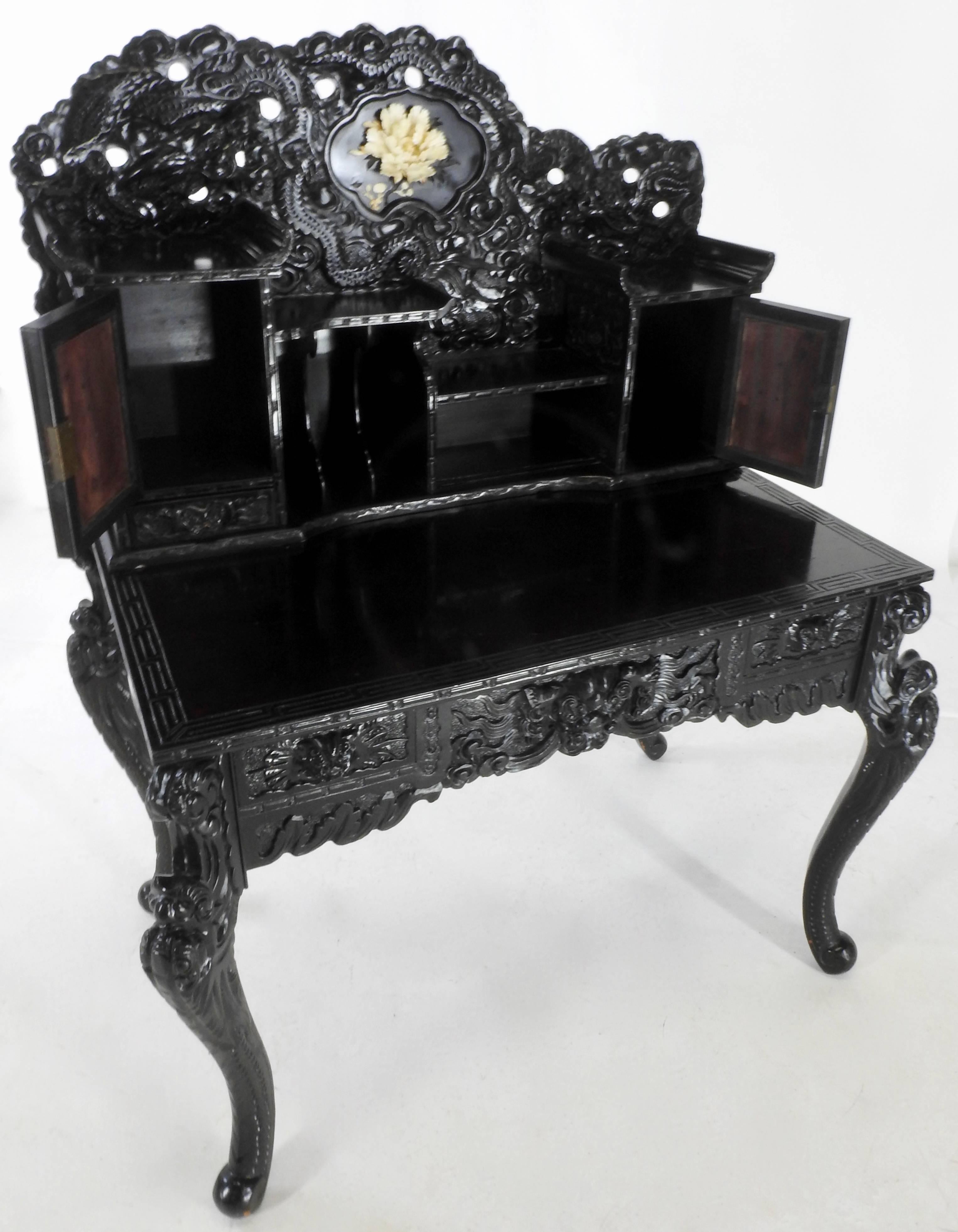 Intricate hand-carved flowers made of ivory grace this lovely ornate secretary from the early 20th century. The secretary has elaborate detailing in the black lacquered wood. Has several doors and shelves to accommodate your treasures. This all sits