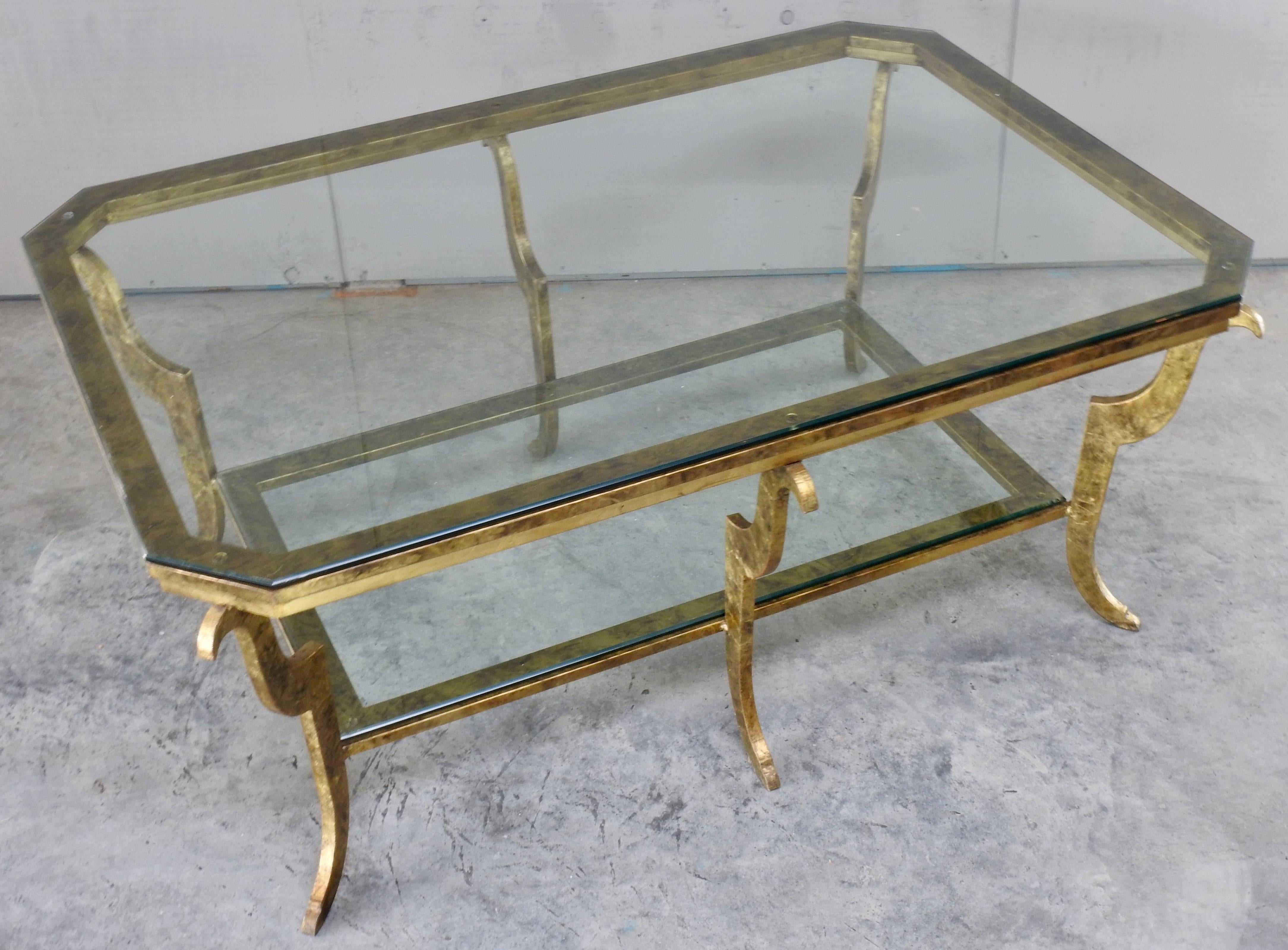 Two layers of heavy beveled glass adorn this Hollywood Regency cocktail table. The glass sits atop a gilded steel frame with texture. Graceful curved legs complete this look.