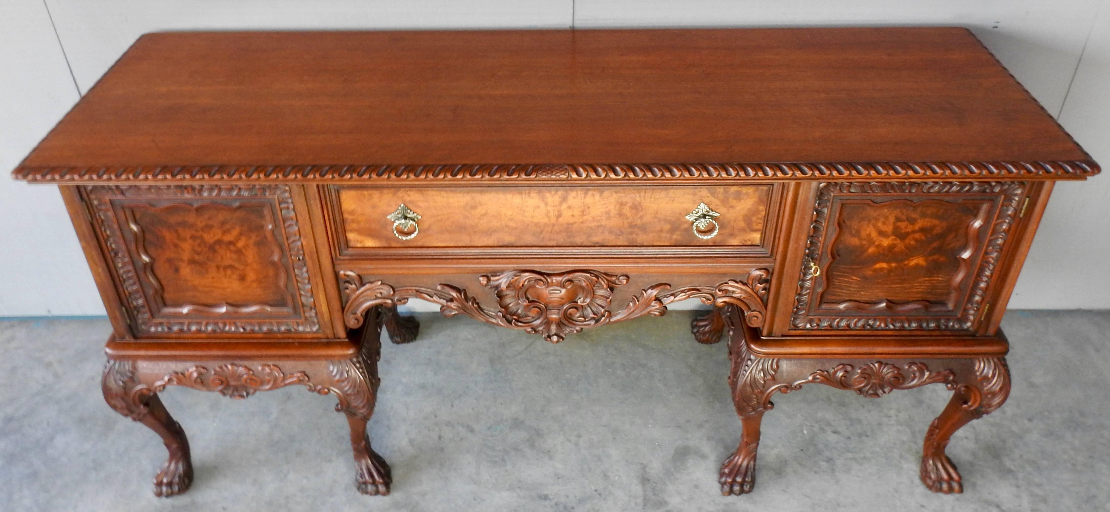 Elaborate Victorian walnut sideboard with richly carved details and rich burl wood. Hairy paw feet extend to graceful curved legs. The dove tailed center drawer has bronze pulls. The side doors open for ample storage. Remains of the tag from a Grand