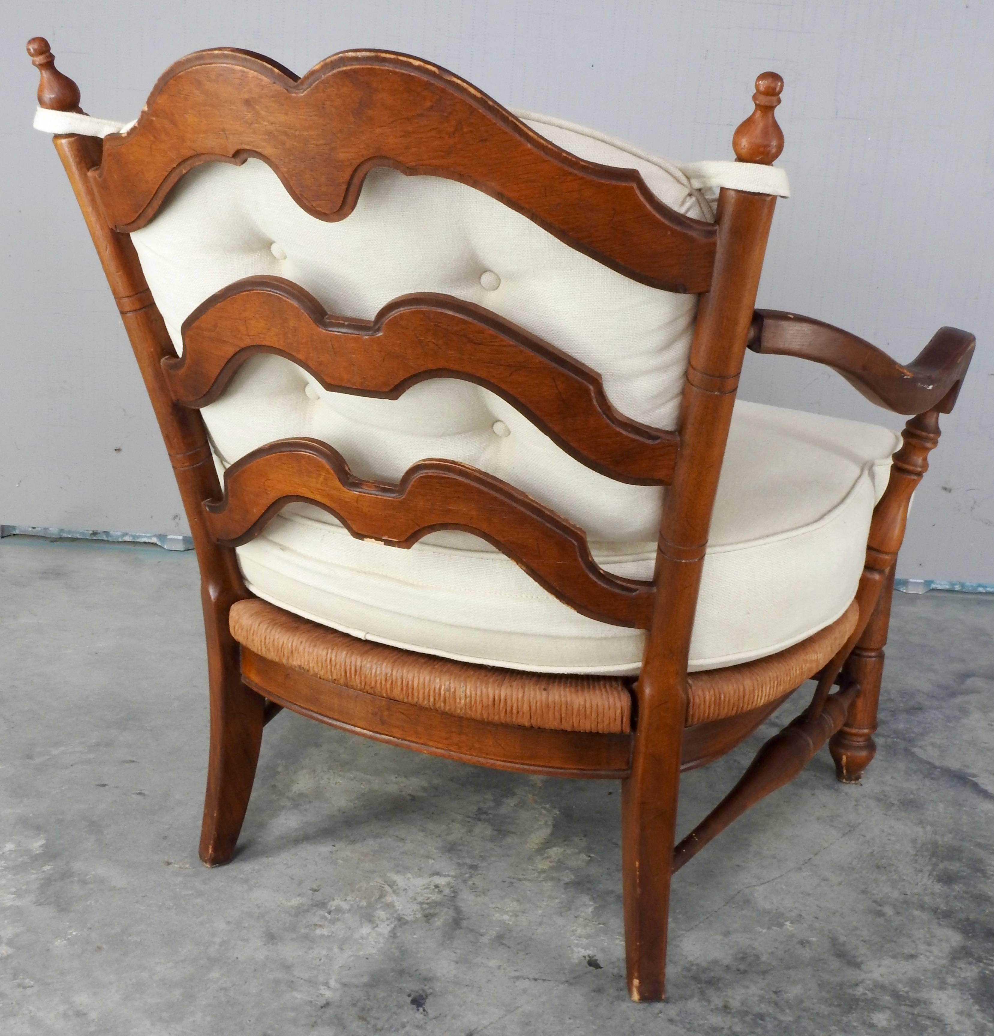 Arches grace the back of this Mid-Century Modern Danish lounge chair. The seat is woven and is topped with a cream colored cushion as well as the back. Turned spindles and curved arms lend to the character of the chair.