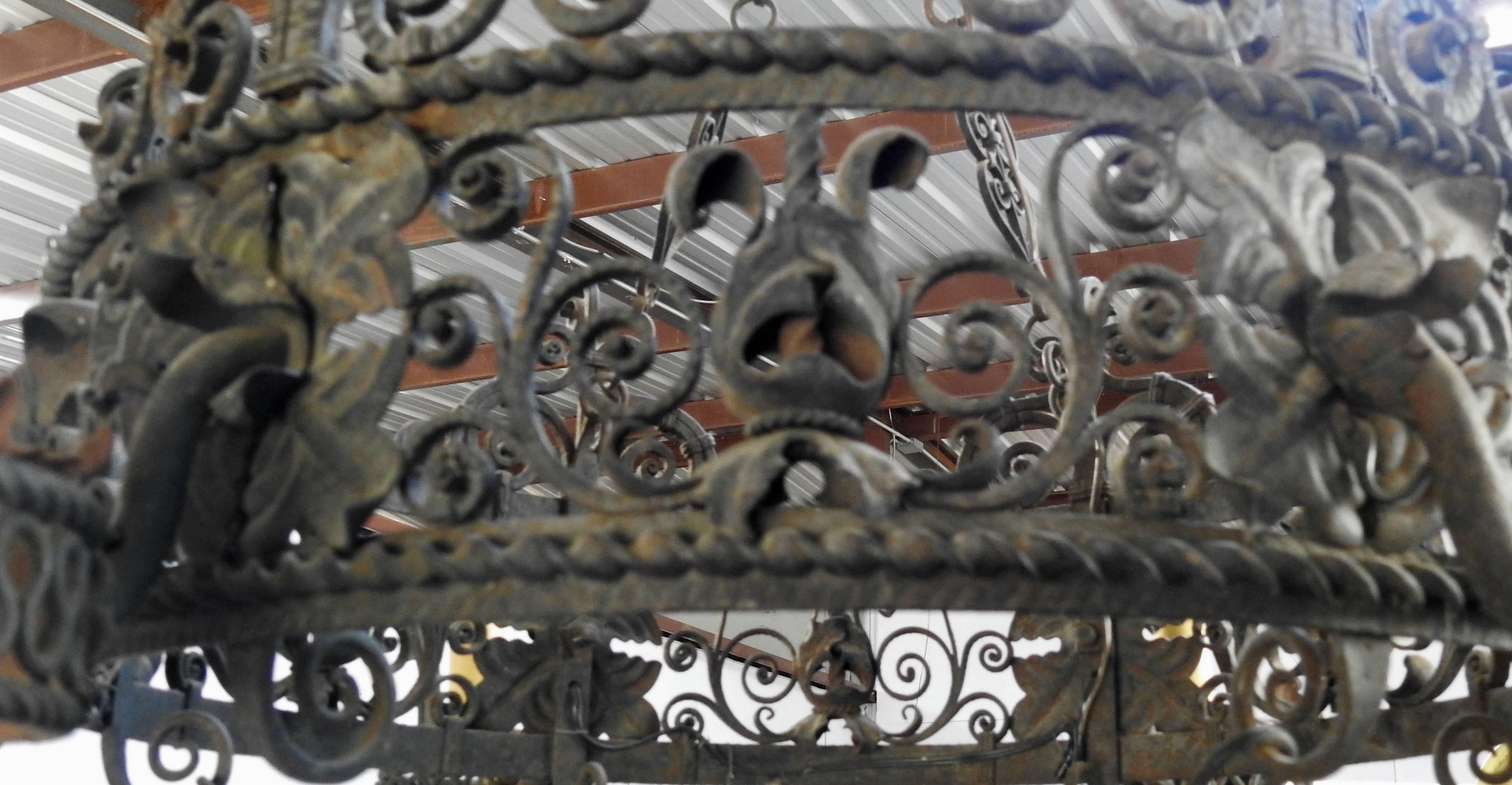 Elaborate wrought iron makes up this outstanding Spanish chandelier. It features ornate scrollwork and rope trim in the iron work. Flowers and leaves add to its character. The chandelier has been rewired and candle covers with drips have been added.