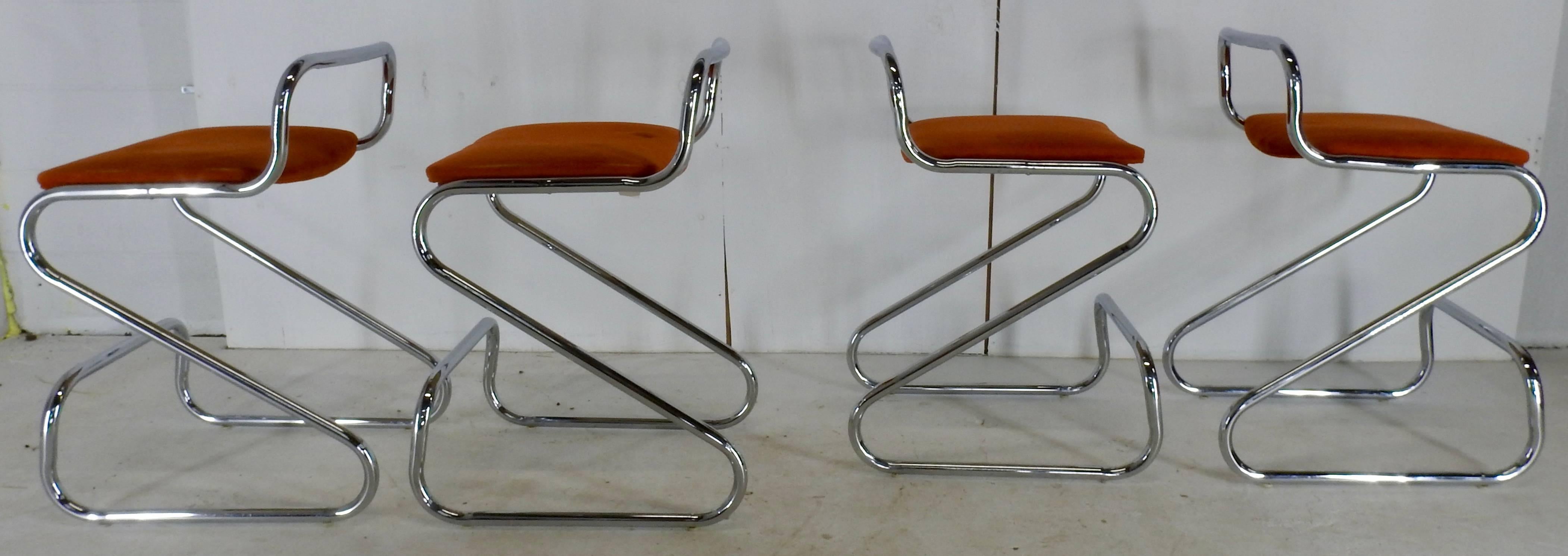 Set of four Daystrom Furniture Co. chromium and fabric stools from the Mid-Century Modern era. Graceful curves make up the form of the stools and are topped with the urethane foam seats covered in a rust covered fabric. This company was in business