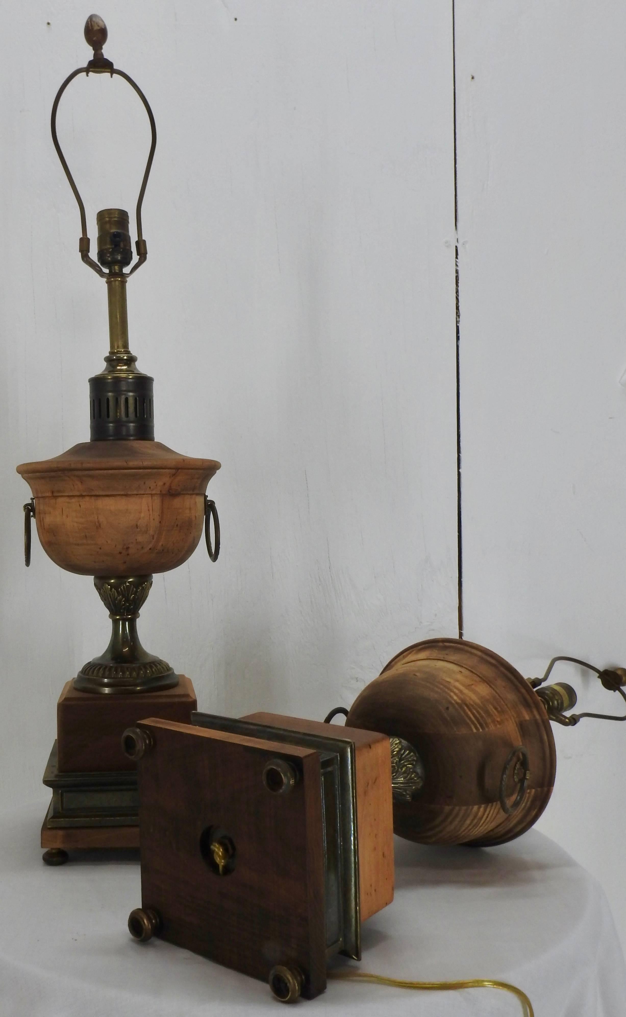 A pair of Frederick Cooper lamps featuring waxed walnut and antique brass finished metal enhancements. New socket interiors and gold cords have been added. The square base supports the column and a turned round font has rings on two sides. On the