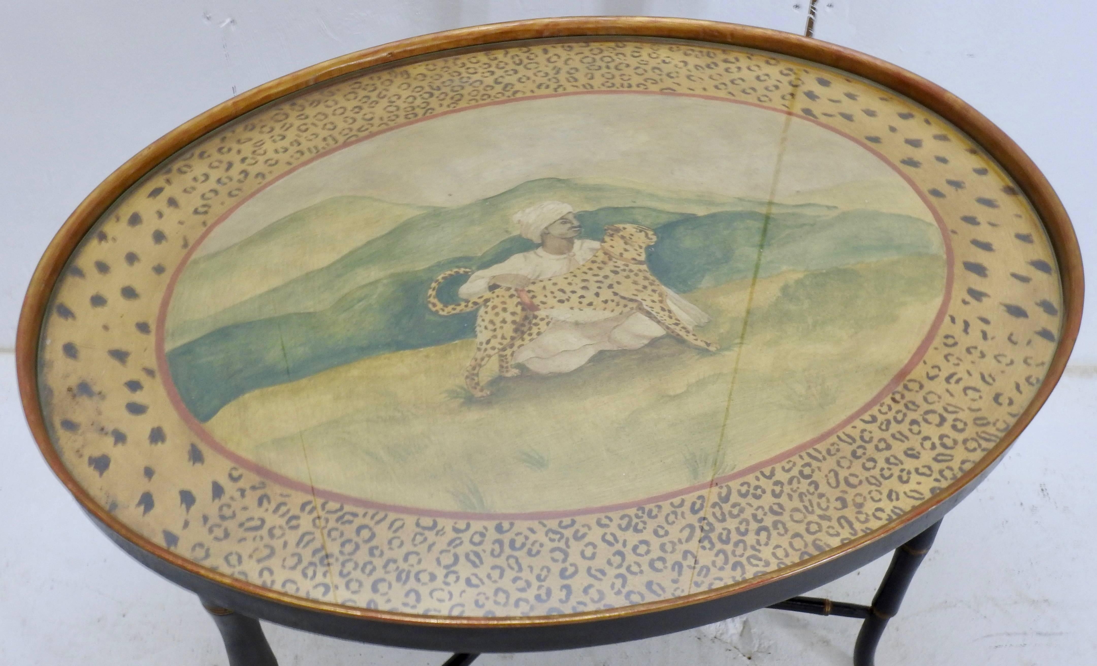 Elegant Chippendale style wooden legs are painted black with gold accents to support the hand painted oval top. The painting has a man with a turban petting a leopard and the perimeter is surrounded by leopard spots.