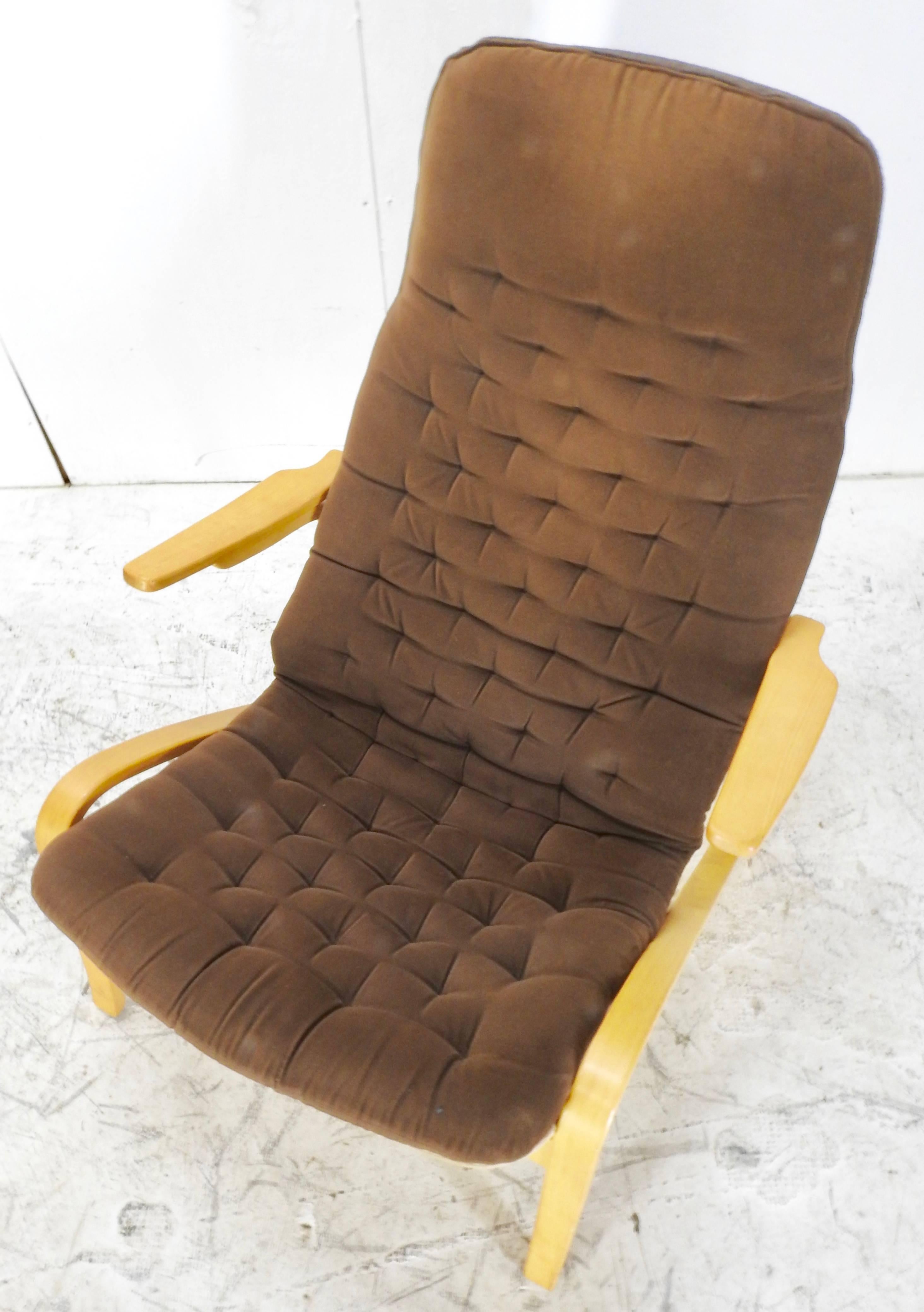 We are featuring a Danish modern lounge chair by DUX. This chair features a button tufted, brown upholstered seat cover applied to the high back and flanked by curved armrests. The saddle seat rises on a curved frame. The chair is marked “DUX”.
 