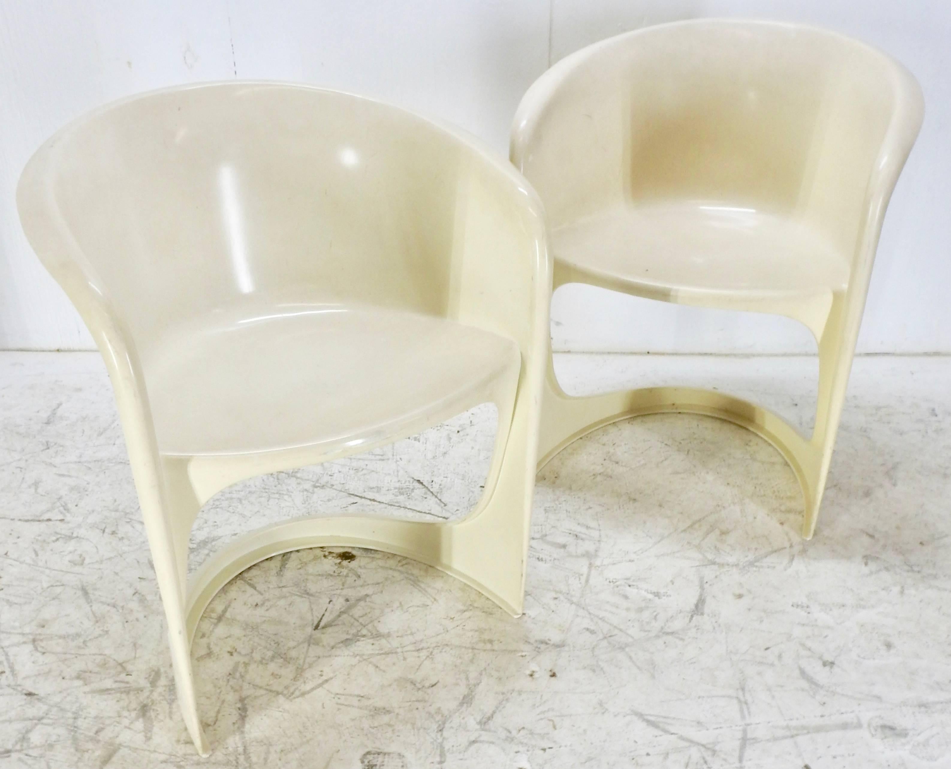 This is a stunning pair of Mid-Century Modern molded chairs by the Danish firm Cado. These were designed by architect and designer Steen Ostergaard (born 1935). Each chair features an arch crest with rolled edge over a molded barrel back with