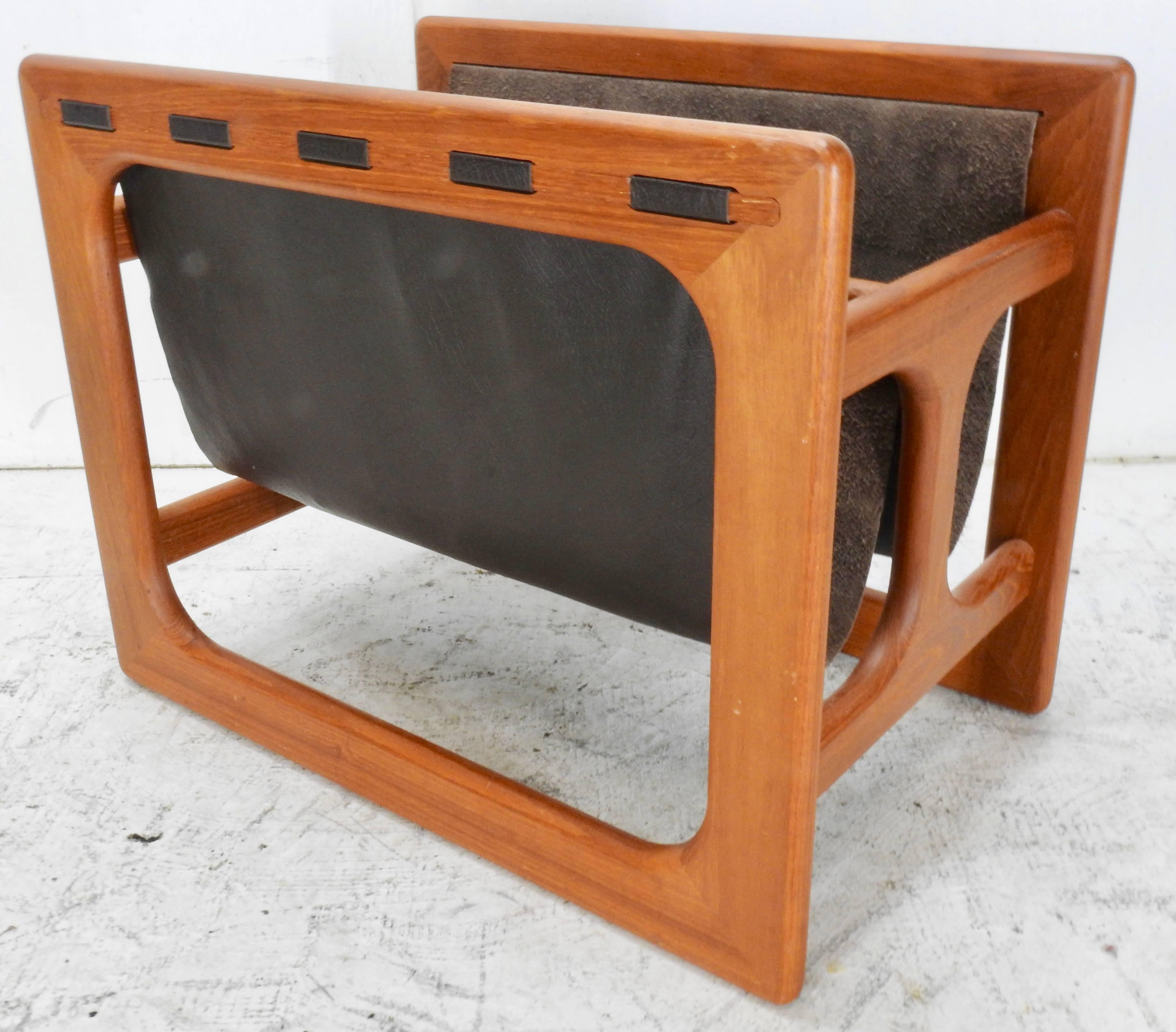 This is a very nice Danish Modern teak and dark brown leather magazine rack designed by Salin Møbler. The 1980s era Minimalist design has two sling compartments that are suspended by wide visible straight line stitches.
 