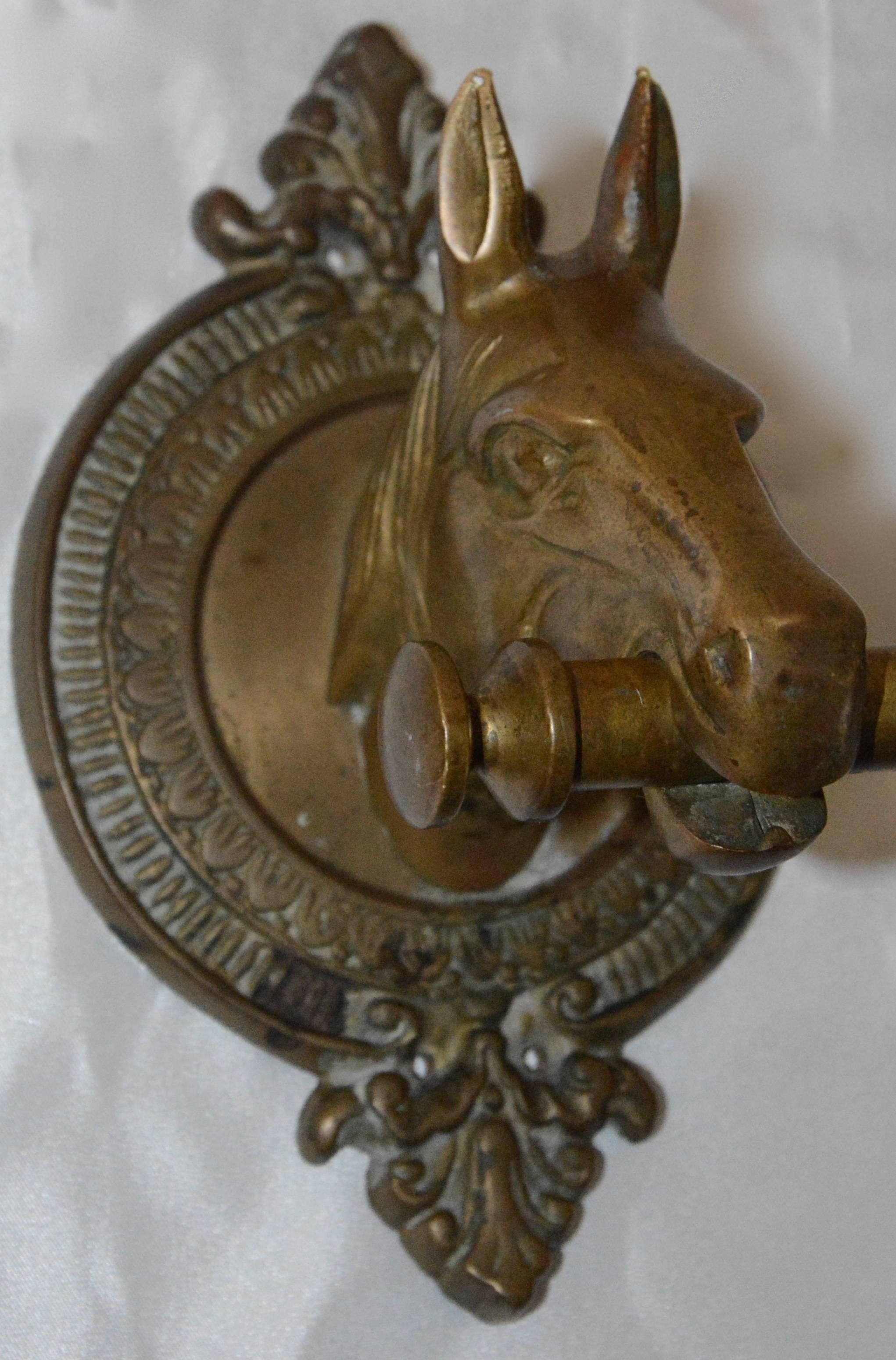 Featured is a heavy brass horse head coat rack. This piece features two figural horse heads mounted to wall plaques with a long rod between them held in their mouths. The cast brass has nice details. Five coat hooks are secured to the rod.
