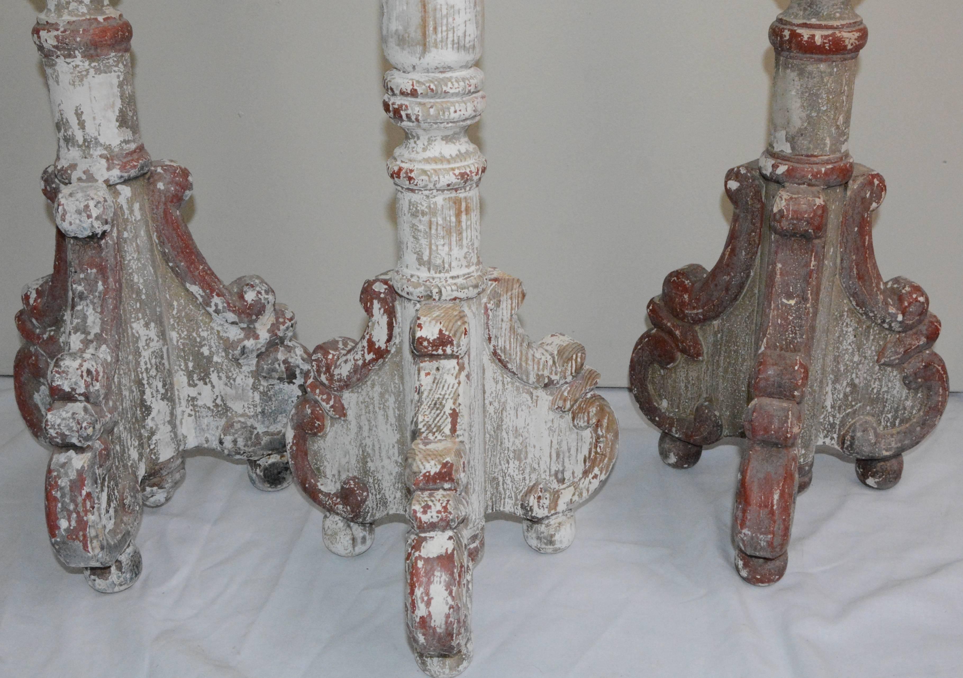 This is a nice group of large floor candlesticks. The three matching wooden items feature ornate splayed legs which are supported by ball feet. Each turned column is topped by a metal sconce, with two of the sconces having an upward rising petal