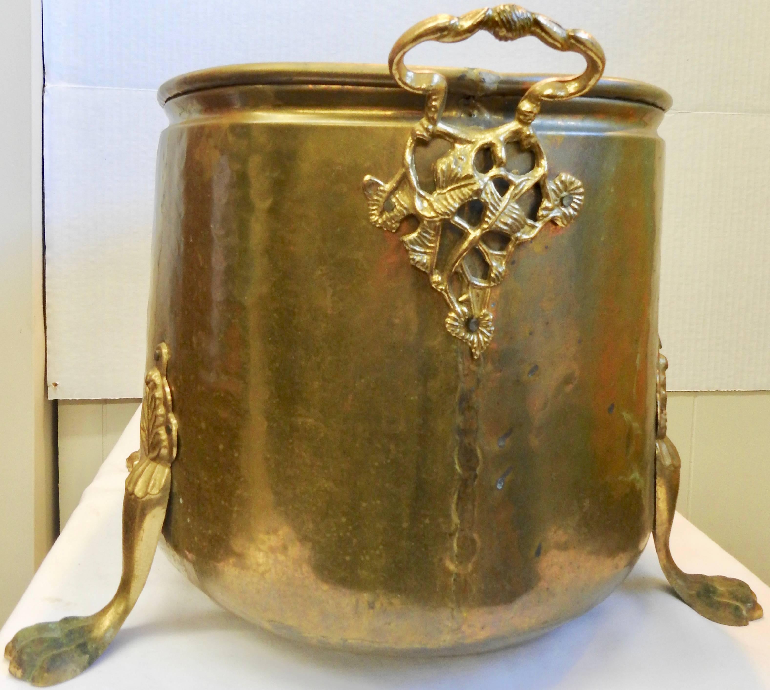 This midcentury brass fire bucket has been beautifully crafted. The body of the bucket is lightly hammered and it sits atop cast footed legs. The cast brass pair of handles has ornate detailing.