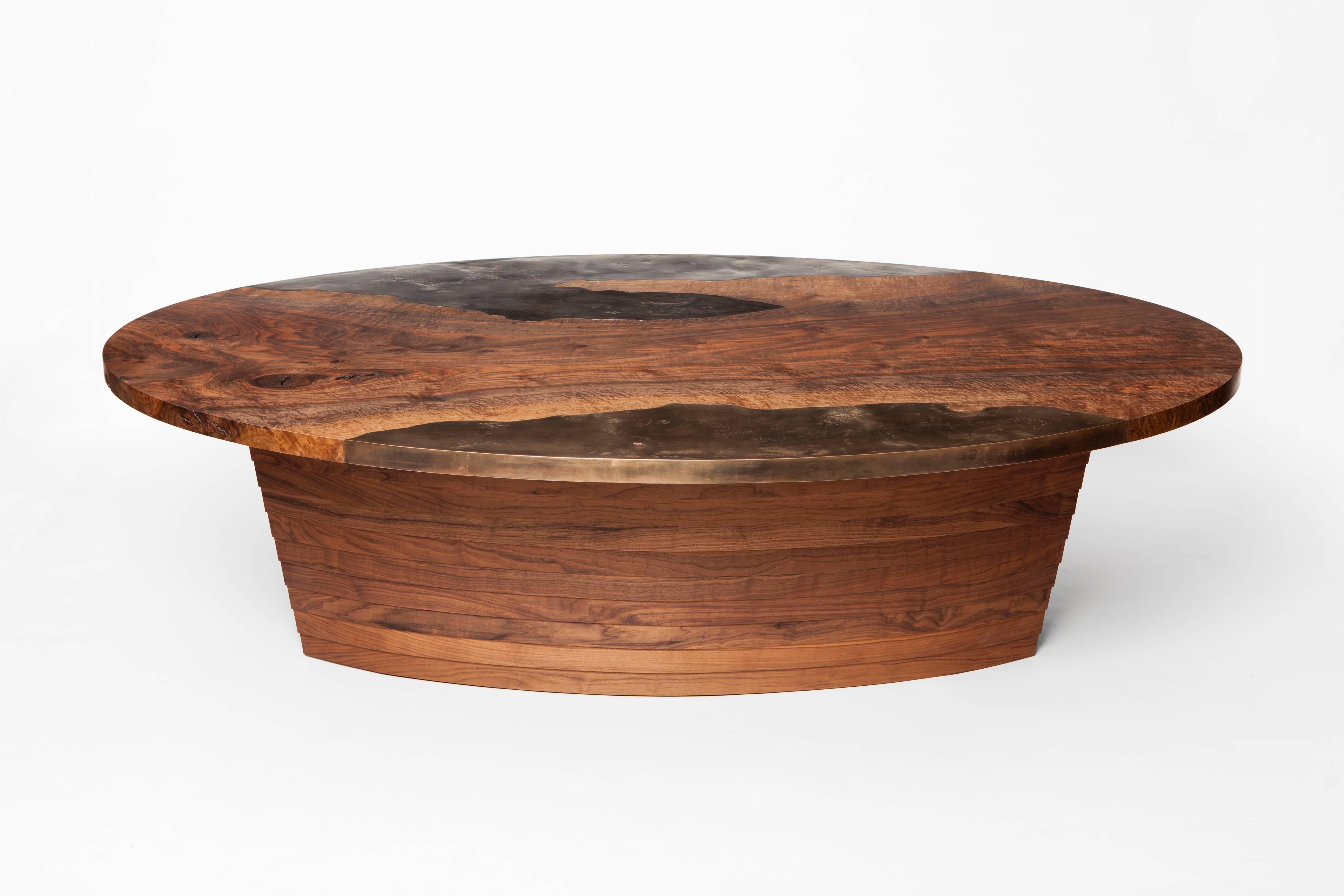 Der in Nordkalifornien handgefertigte Tisch Pangaea von Taylor Donsker zeichnet sich durch zwei gegossene Bronzekanten aus, die nahtlos in die Platte aus stark gemasertem Bastogne-Nussbaum integriert sind und auf einem dampfgebogenen und