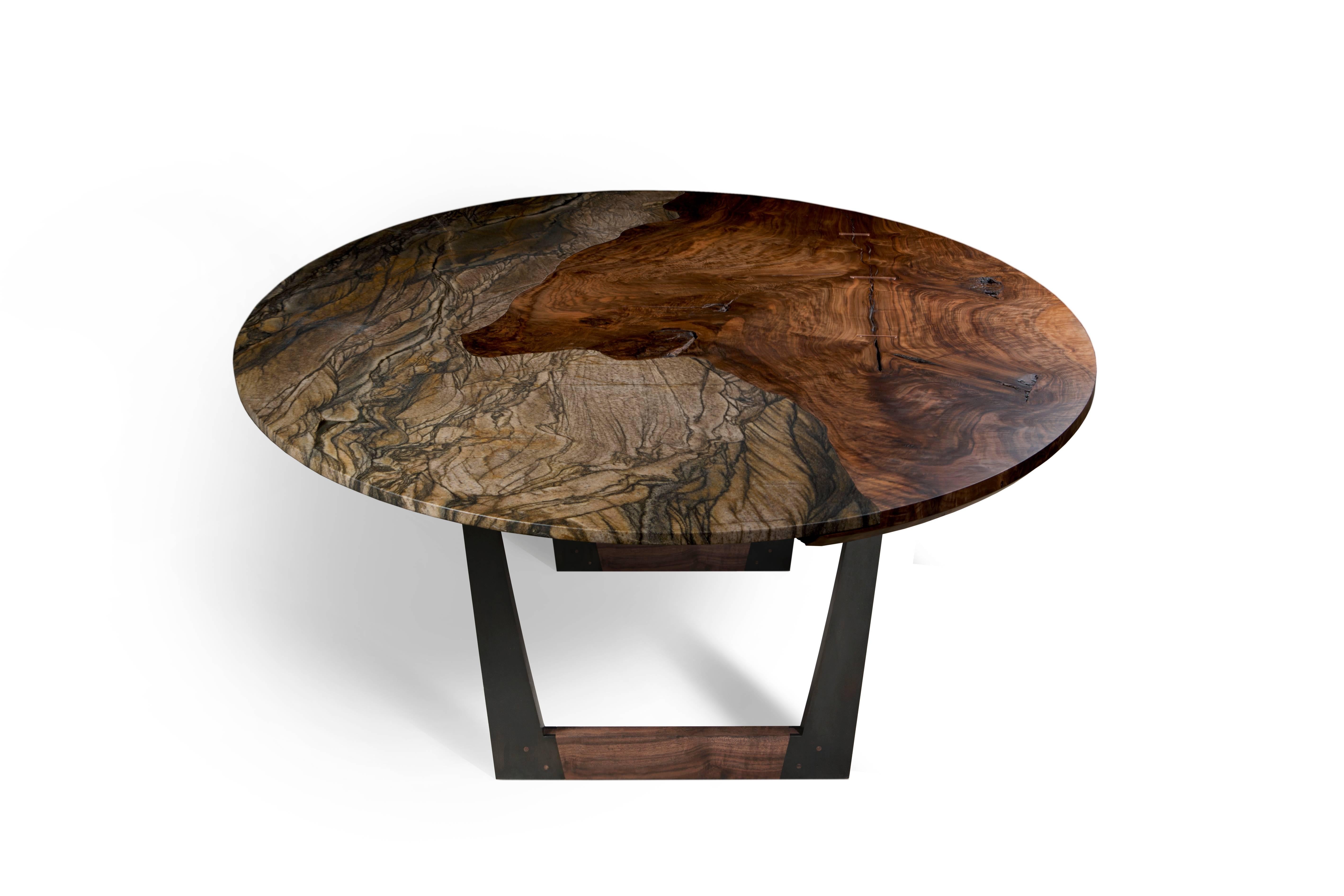 The Granite Pangea table by Taylor Donsker features a single granite slab seamlessly inlaid into the top of a single slab of highly figured Bastogne walnut that is resting upon two U-shaped blackened steel and Bastogne walnut bases. The result is a