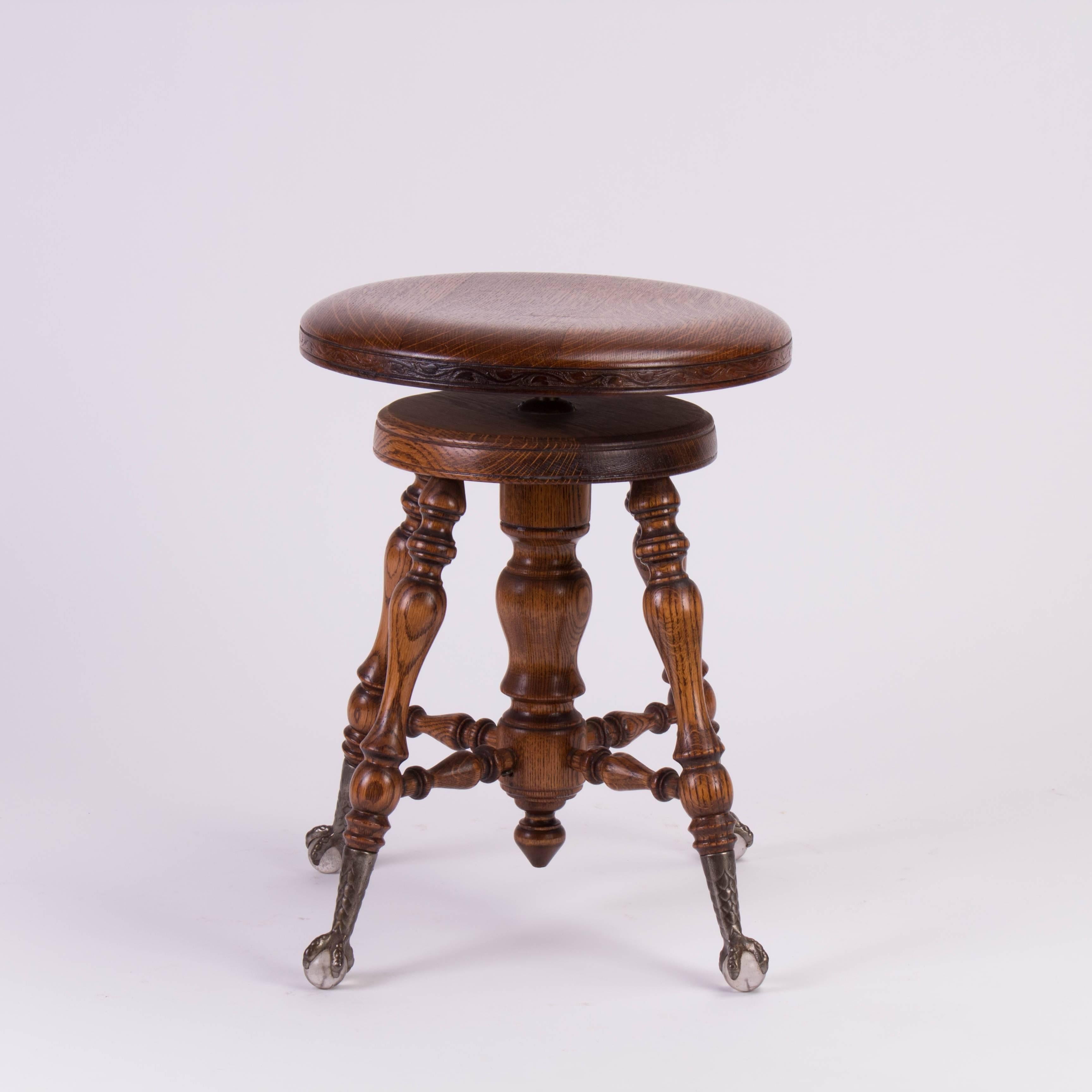 Late Victorian 1800s adjustable piano stool in solid wood, features four beautiful copper patina talon claw feet each grasping a clear crystal ball.