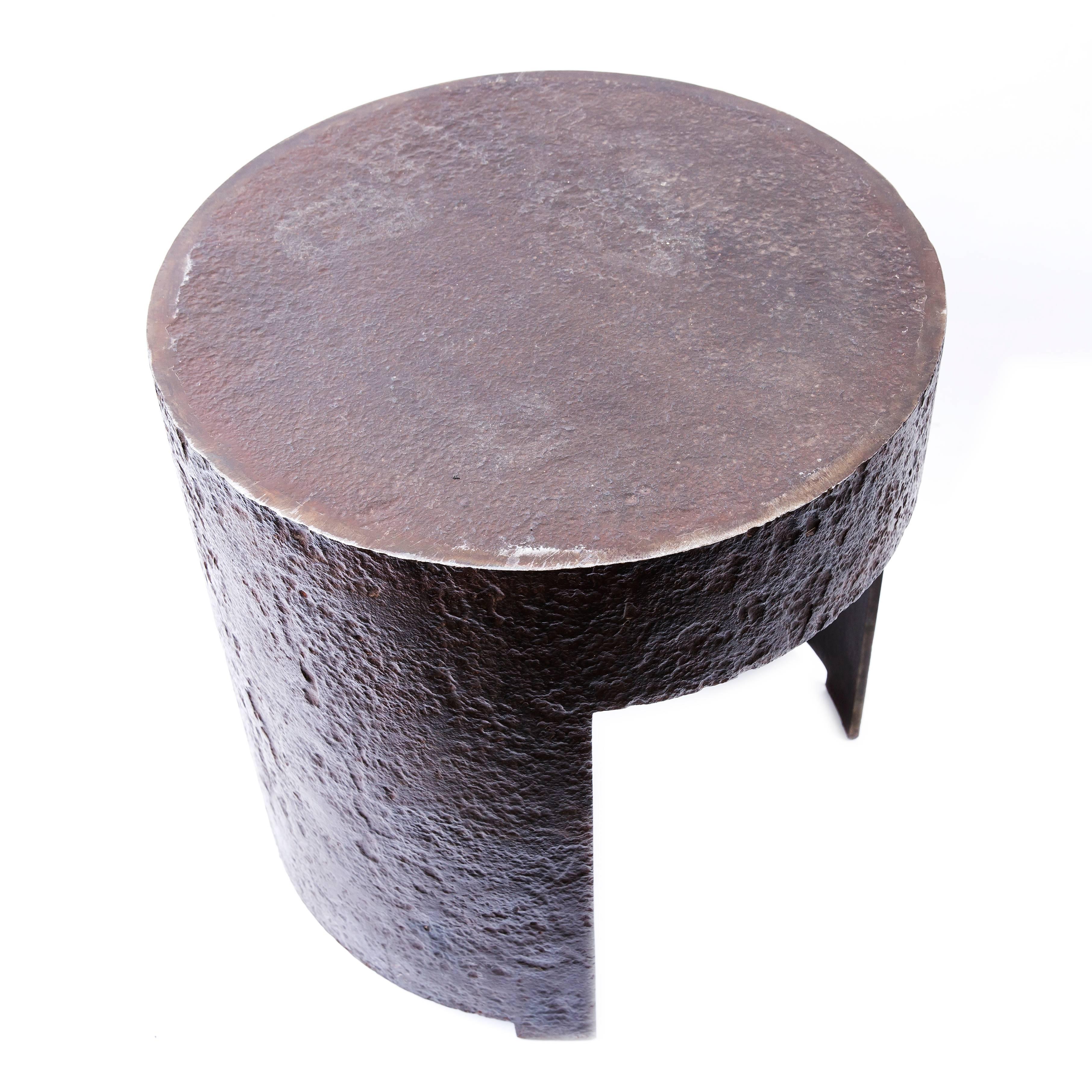 Designed iron side table.

This incredibly modern and imposing creation is not only sculpturally respectable and imposing but it is highly multi functional. 
It's circular top surface can be used for sitting, an assortment of coffee and side table.