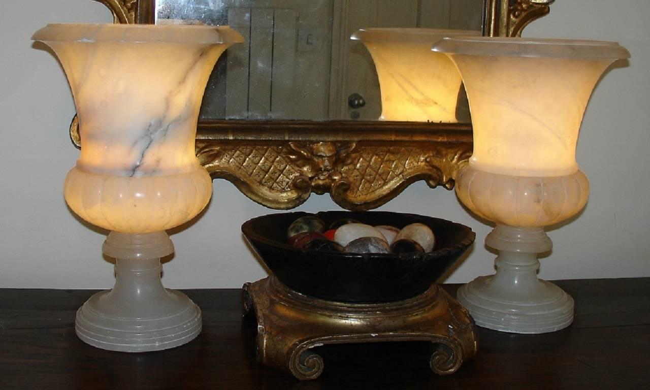 A pair of French 1960s alabaster lamp urns. Classical design, simple and unrestrained which will blend with most interiors. Gives off a warm glow when lit and look equally elegant when not.