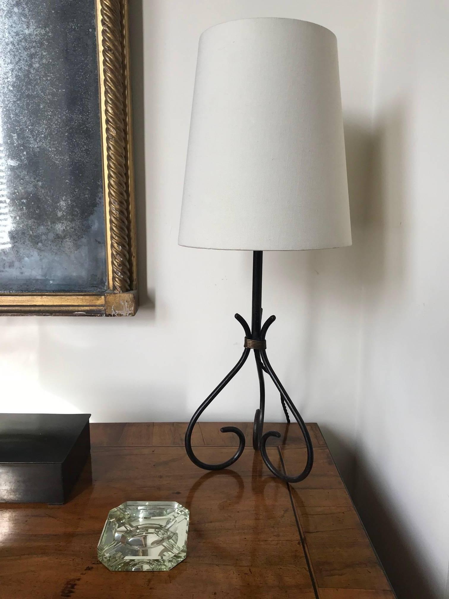 A black iron table lamp with twisted gilt metal rope detail in the manner of Jacques Adnet, French, circa 1950s.