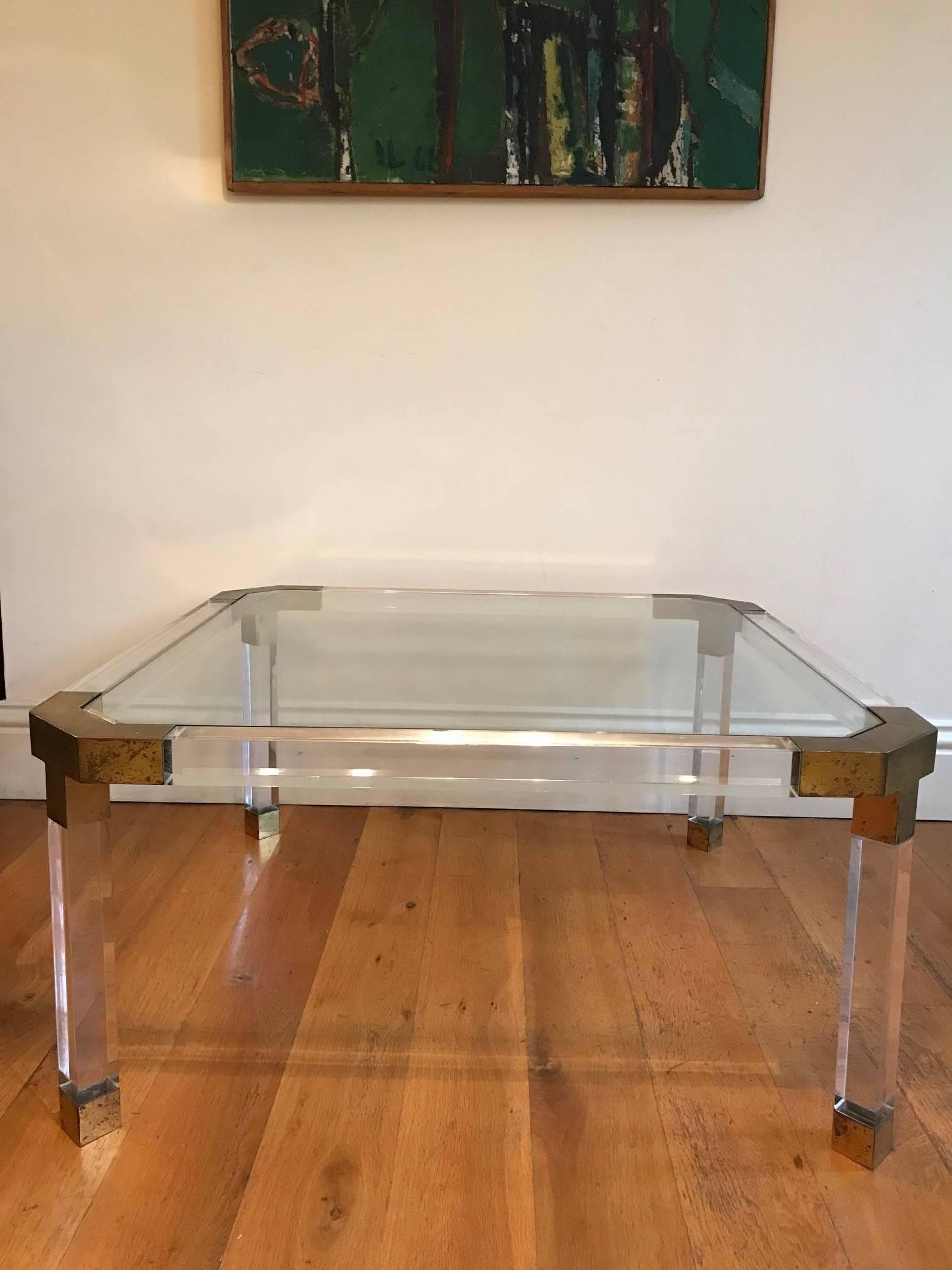 An elegant gilt metal Lucite or Perspex and glass square coffee table, French, circa 1970s.