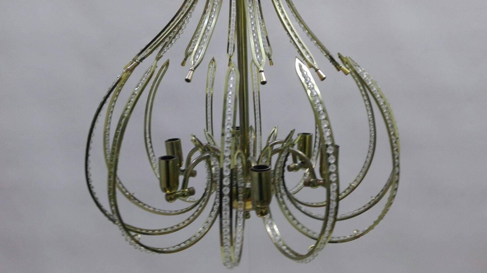 Elegant pair of chandeliers with modern lines made with quality materials such as brass and crystal.