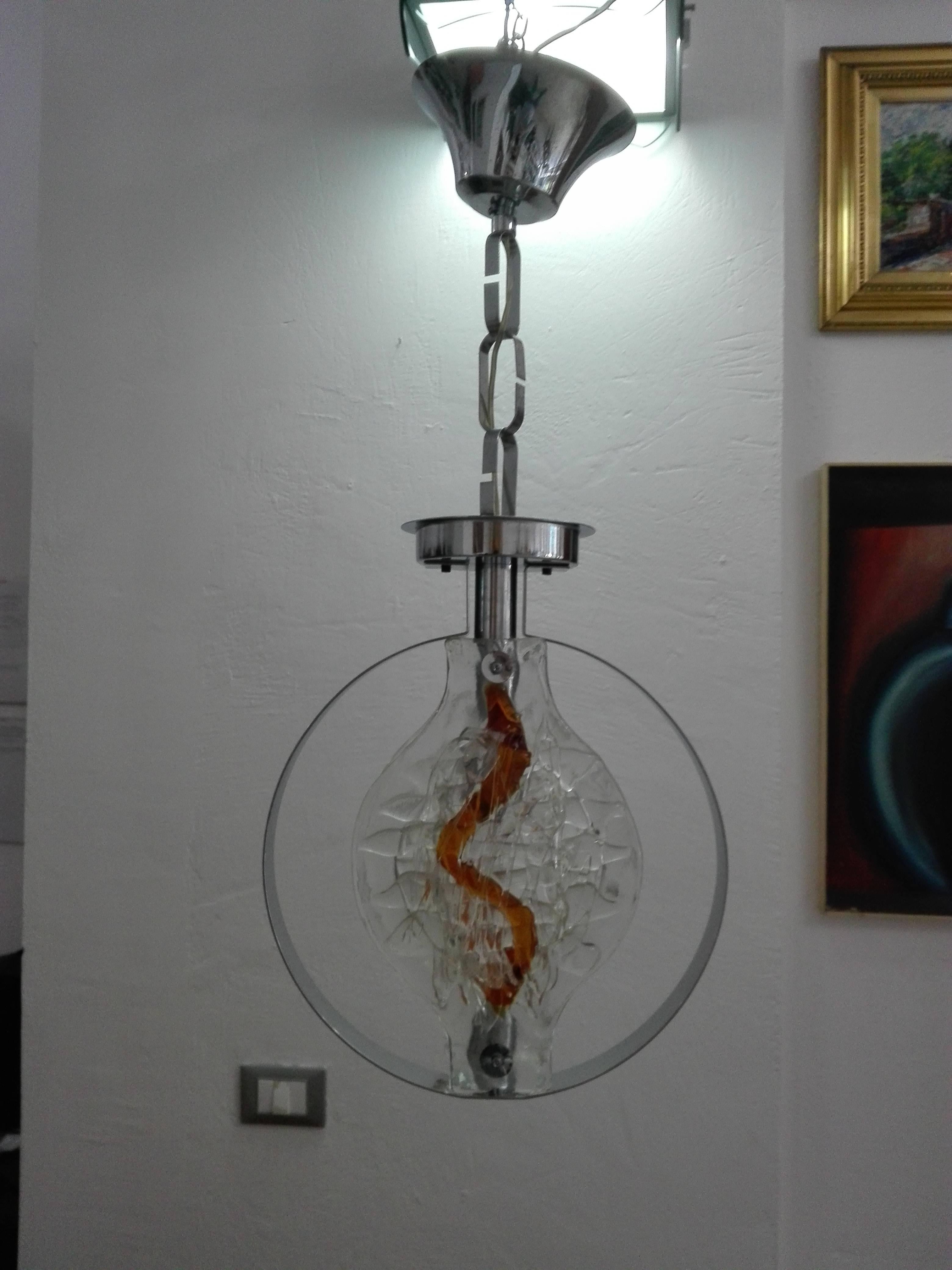 
Clear blown glass chandelier with amber inclusions.
Chromed steel structure with two handmade glass plates.
1970s Mazzega Murano production.