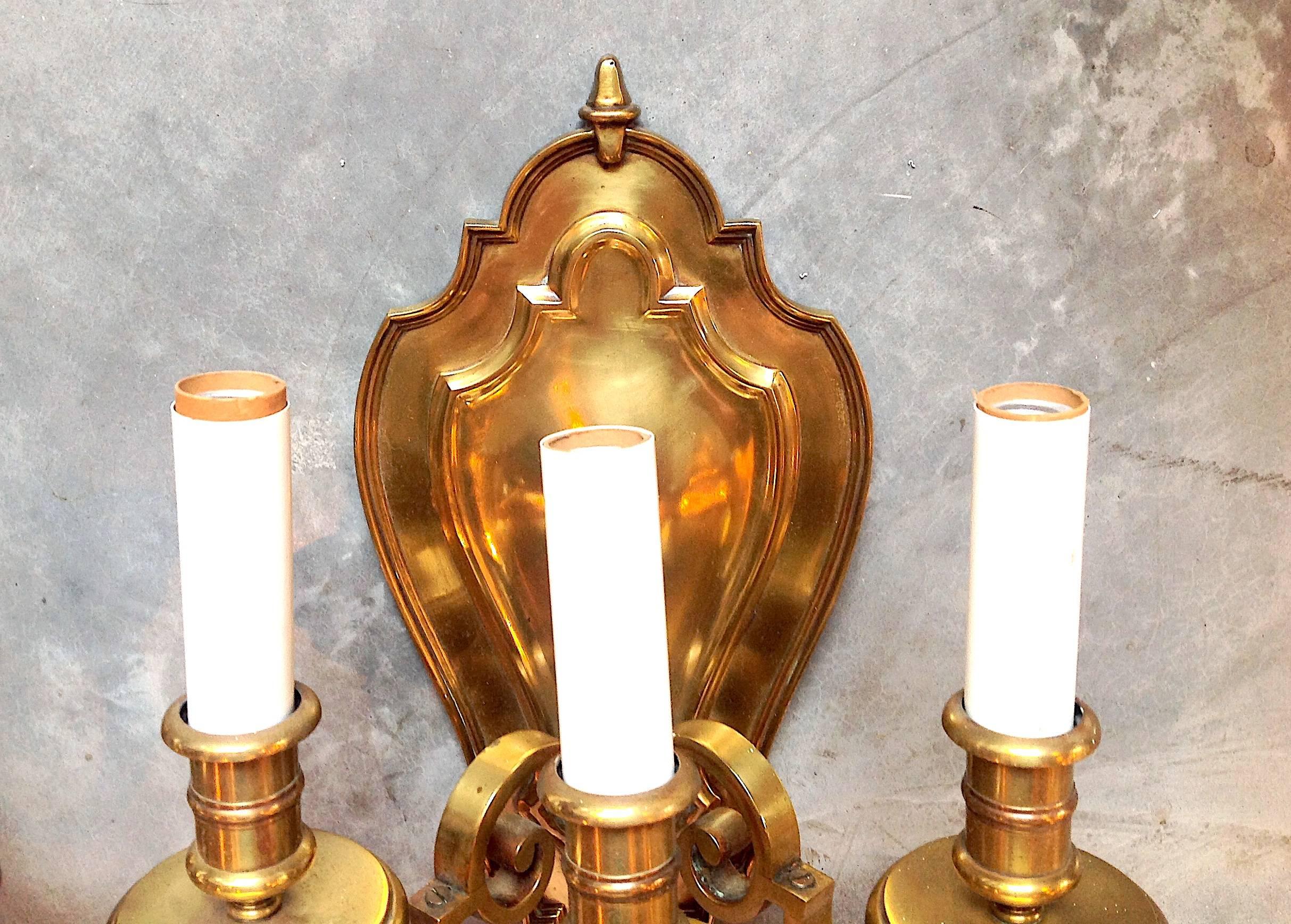 Pair of three-light English cast brass wall sconces with shield back, Edwardian style, circa 1920s, possibly Bradley & Hubbard or E.F. Caldwell.