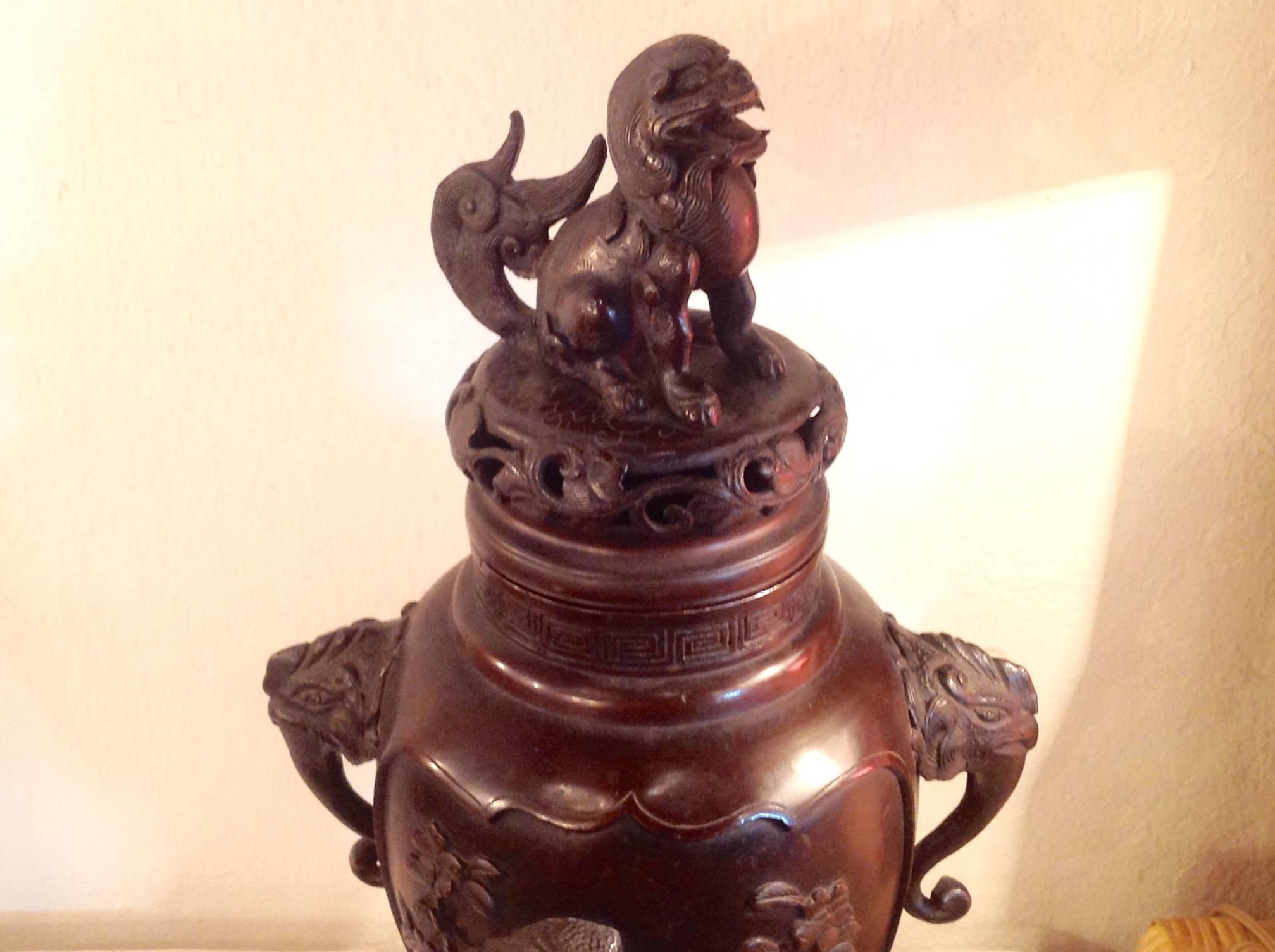 Asian bronze urn or censer, handcrafted with hidden art on inside of bottom base, symbols on border of base, measures 19 inches high and 10 inches wide.