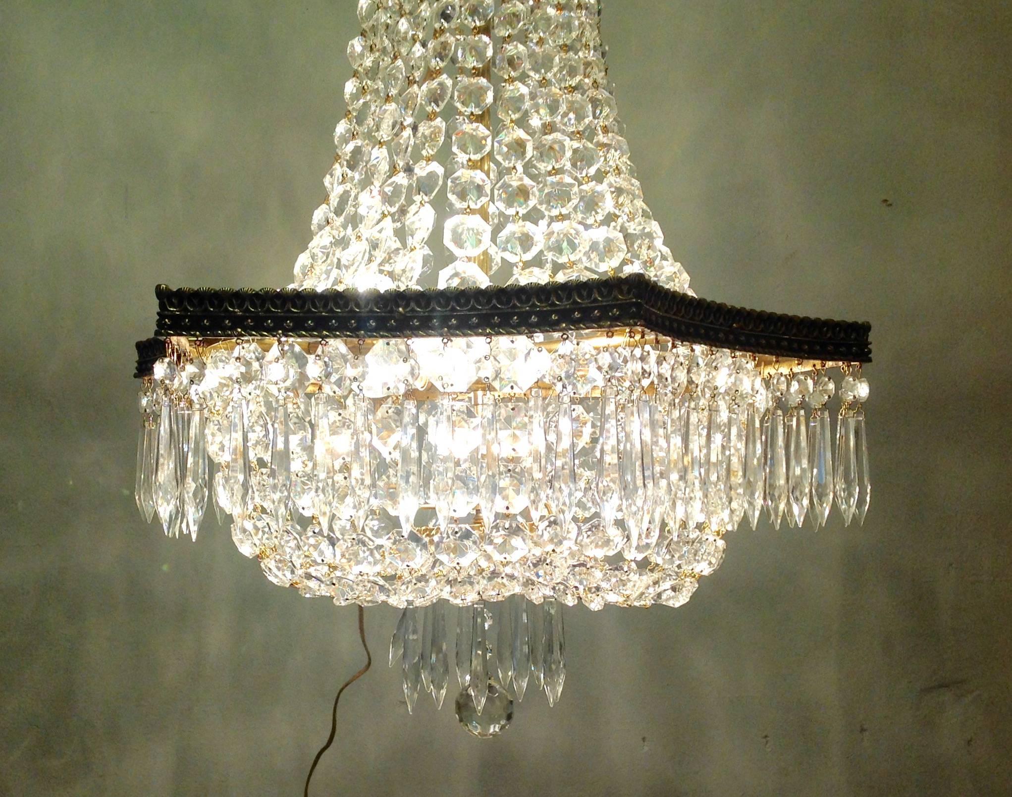 Spanish crystal Empire chandelier with antique inverted scalloped brass frame with shell motif, circa 1950s. Beaded crystal graduated strands and U-drop prisms are new. Has been rewired to UL standards. Measures 29.5 inches high and 20 inches wide.