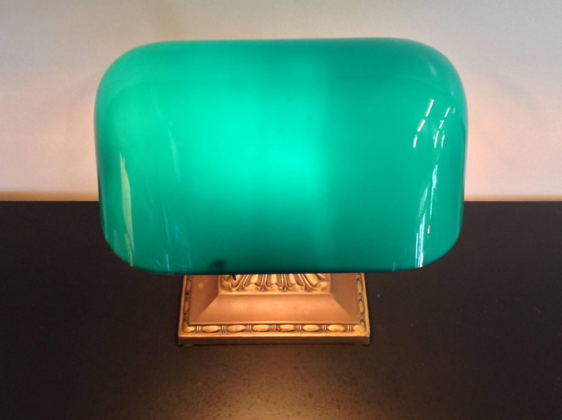 Signed Emeralite adjustable banker's lamp, circa 1916. Brass base and Stand and emerald green cased glass shade. Has been rewired to UL standards. Measures 7 inches wide and 13 inches high.