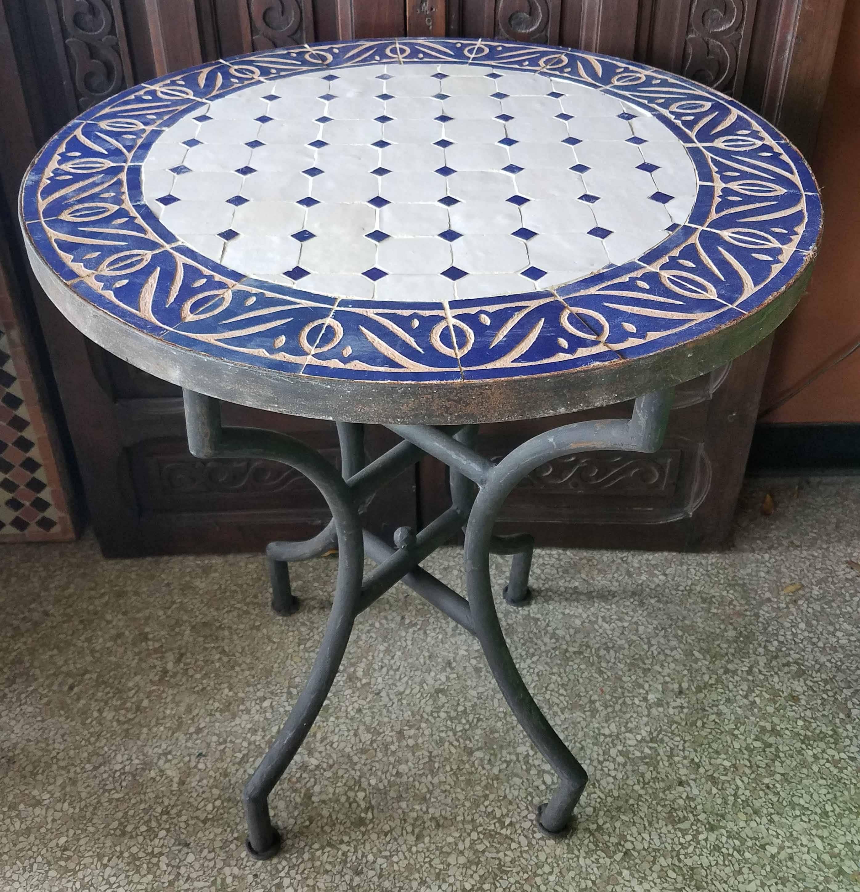 100 % glazed round. White and blue Moroccan mosaic table measuring approximately 24″ in diameter. For both indoors and outdoors. Great as a cocktail table. Vibrant color. Intricate patterns. Included in the price is a wrought iron folding base.