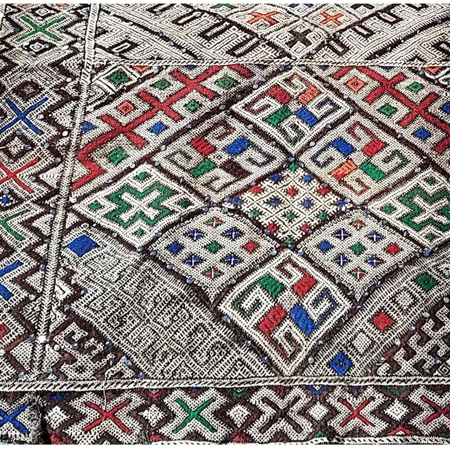 A rare Moroccan Berber carpet (or runner) measuring approximately 12' x 4'. Great for hallways, odd shape rooms or hanging on extra tall walls. Colors including blue, green, orange and burgundy. Sequins sewn in throughout. Please call us or email us
