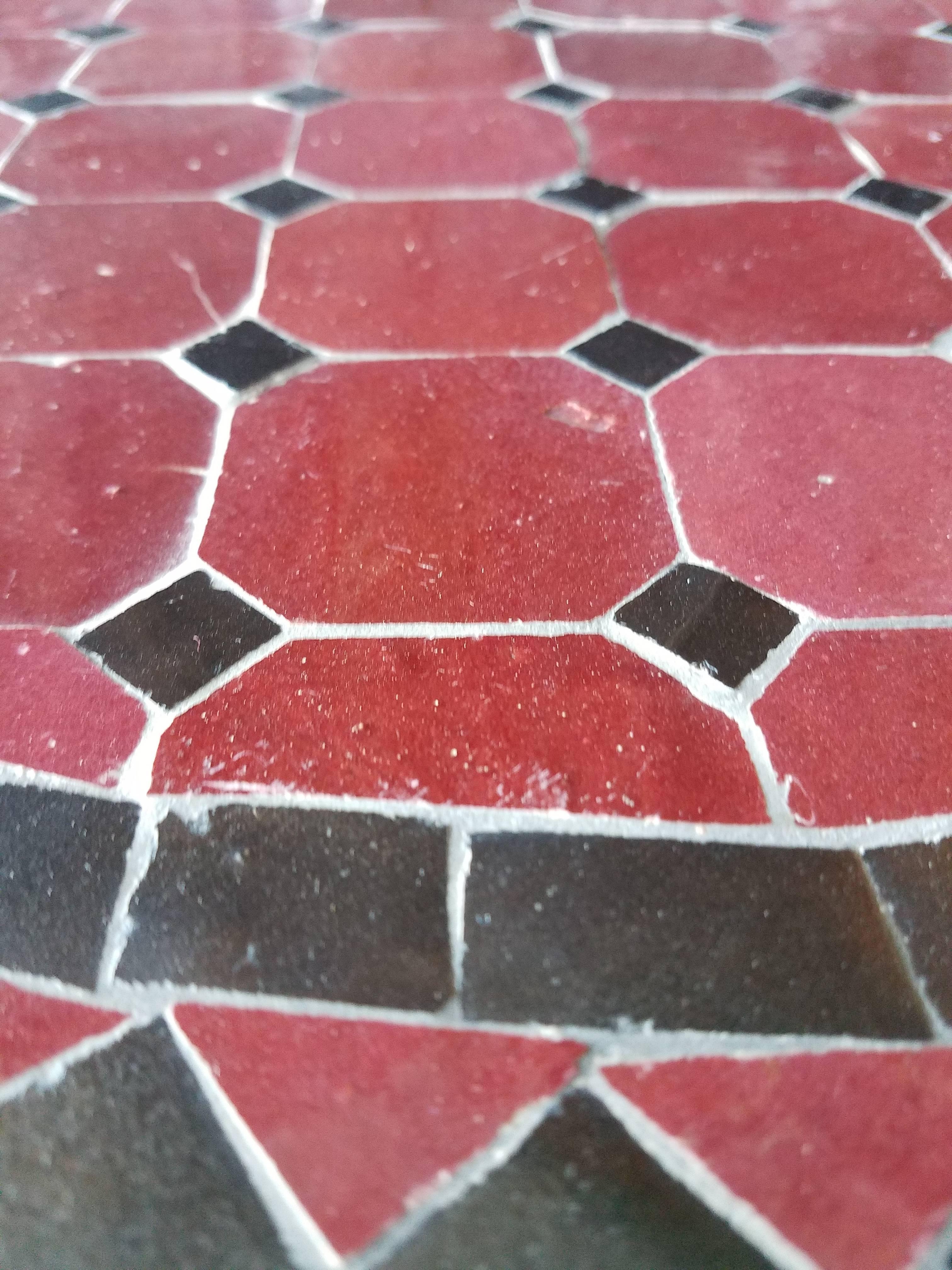 100 % glazed round. Burgundy and black Moroccan mosaic table measuring approximately 24″ in diameter. For both indoors and outdoors. Great as a cocktail table. Vibrant color. Intricate patterns. Included in the price is a wrought iron folding base.