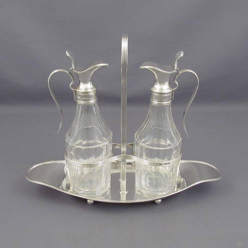 A rare antique English sterling silver oil and vinegar cruet by Bert & Co, London, 1910. Late Georgian style with two silver-mounted cut-glass bottles in an oblong frame with reed borders. Measures: Length of frame 9.5" (24.1cm), weight of