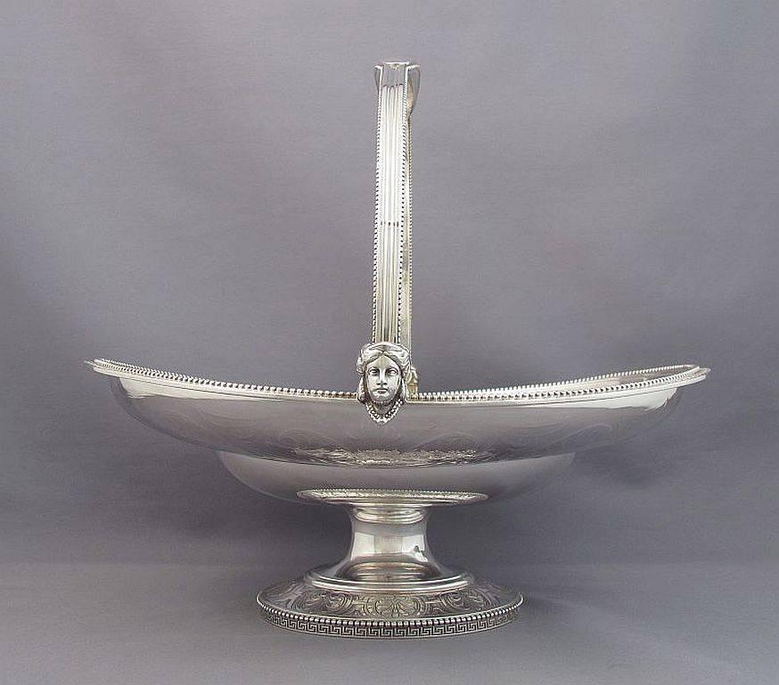 A sterling silver cake basket by Tiffany & Co., New York 1854-1869. Oval body with swing handle on pedestal foot, flat chased with anthemions, applied key pattern and bead border. Monogrammed on the top of the handle. 11.25