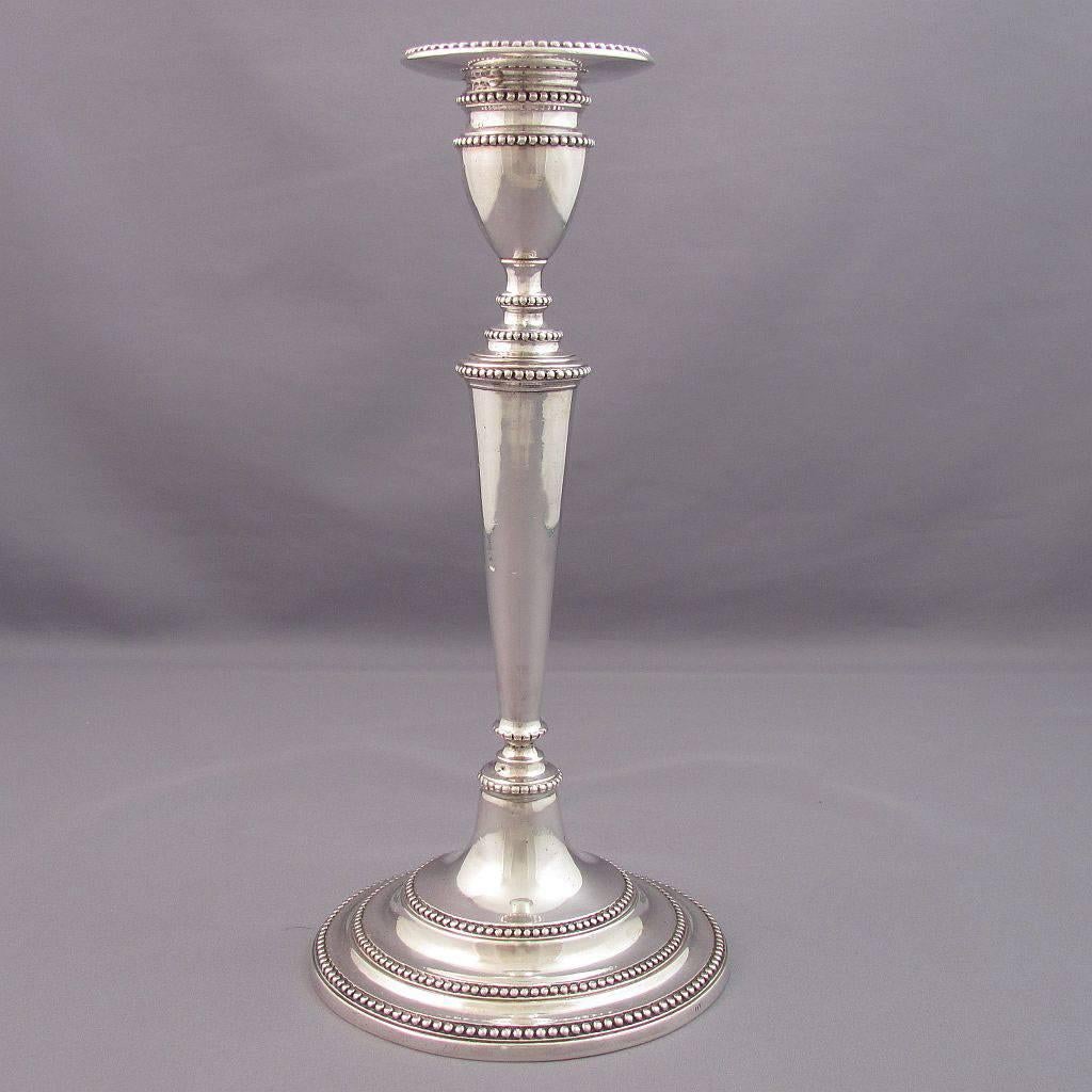 A pair of Portuguese sterling silver candlesticks, Lisbon, circa 1800 by maker DMS. Cast construction, tapered circular columns and stepped bases with bead edges. Measures: 9" high, 26 ozt.