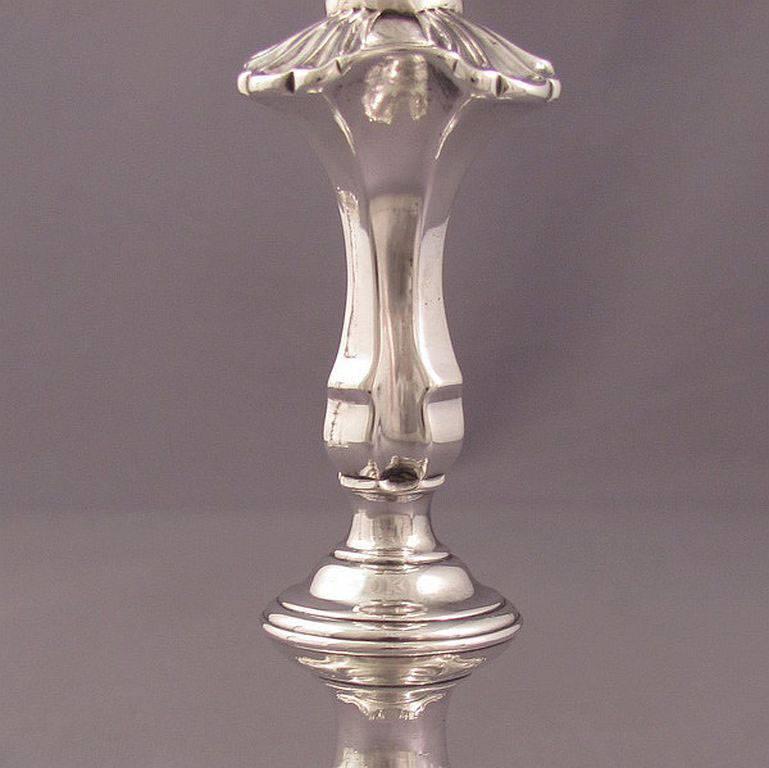 Pair of George II cast silver candlesticks by William Gould, London, 1750. Shaped square bases with shells at corners, the knopped baluster stems and spool shaped sockets. Measures: 8.5
