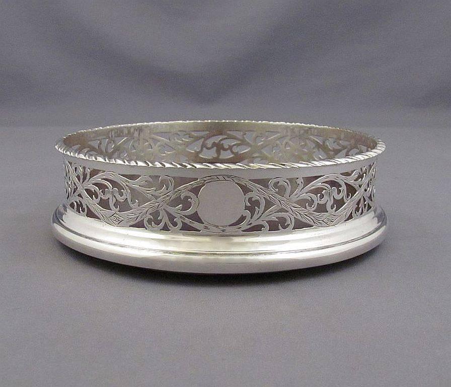 A rare Edwardian sterling silver wine coaster by Carrington & Co, hallmarked, London, 1910. Neoclassical style, pierced and engraved sides with gadroon border, 5