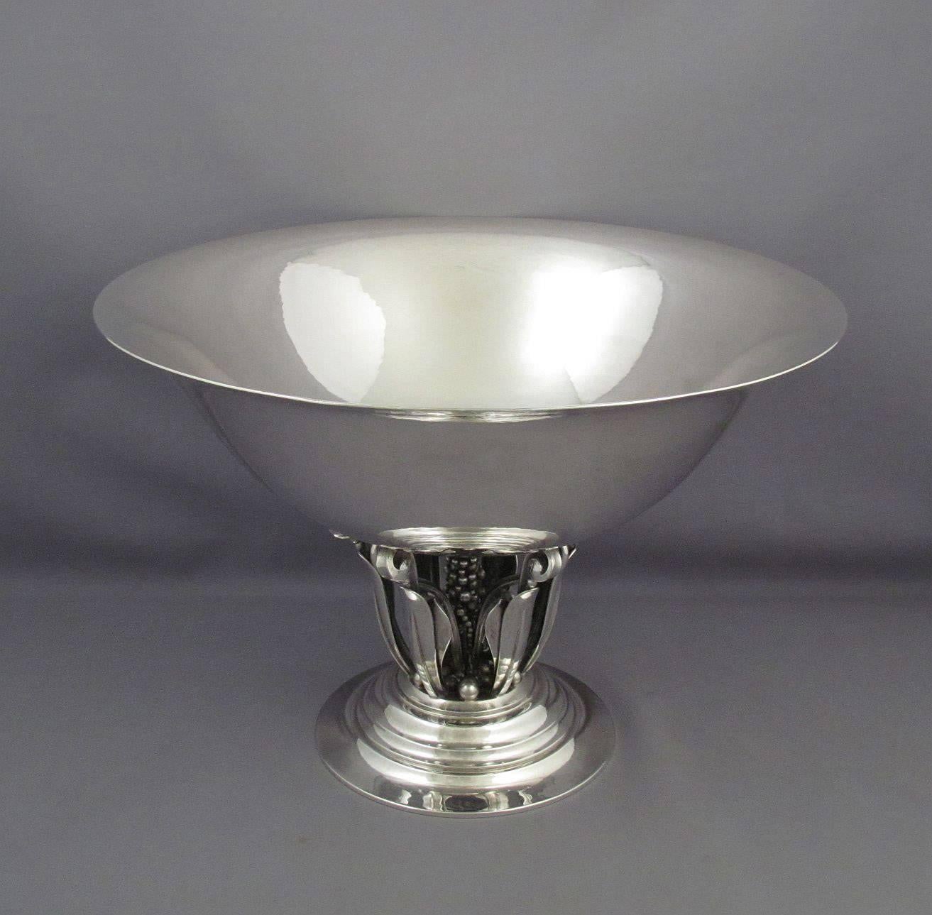 Large sterling silver centrepiece bowl by Georg Jensen with post 1945 marks, design #196 from 1916 by Johan Rohde. The flaring circular bowl supported by an openwork leaf and berry stem, on a stepped and domed circular base.
A bowl of this design