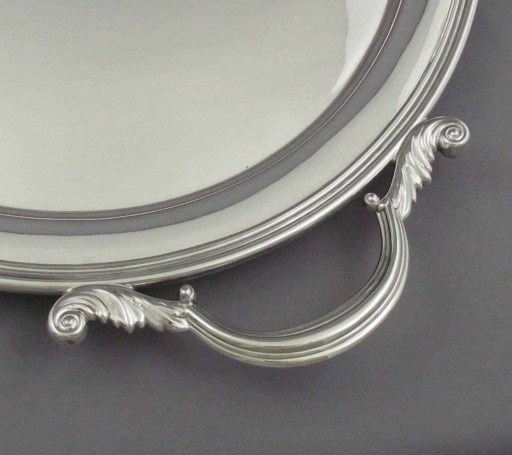 A large sterling silver tea tray by Henry Birks & Sons, Montreal 194. In the George III style, oval with molded border and acanthus capped scroll handles, on four bun feet. Measures: 27 1/8" (69cm) long, 18 1/8" (46cm) wide, 108 troy