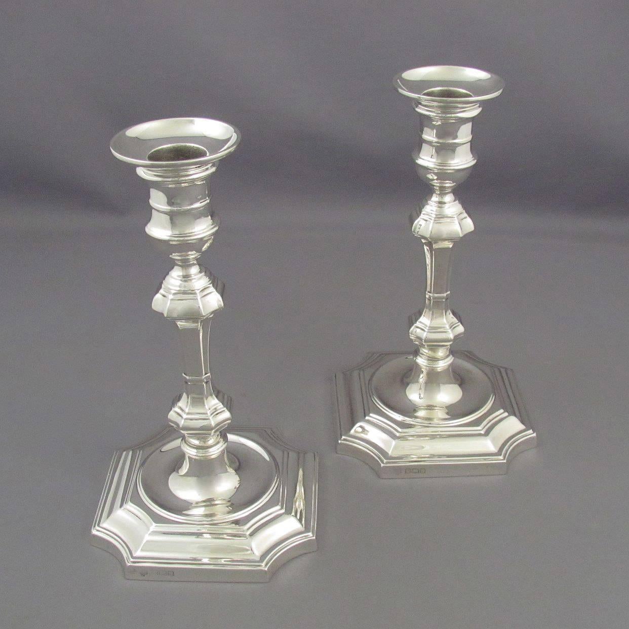 A pair of English sterling silver candlesticks by Hawksworth Eyre & Co., hallmarked Sheffield, 1922. In the George I style, each on stepped square base with incurved corners, double knopped stem and capstan shaped sconce. Retail mark of Ryrie