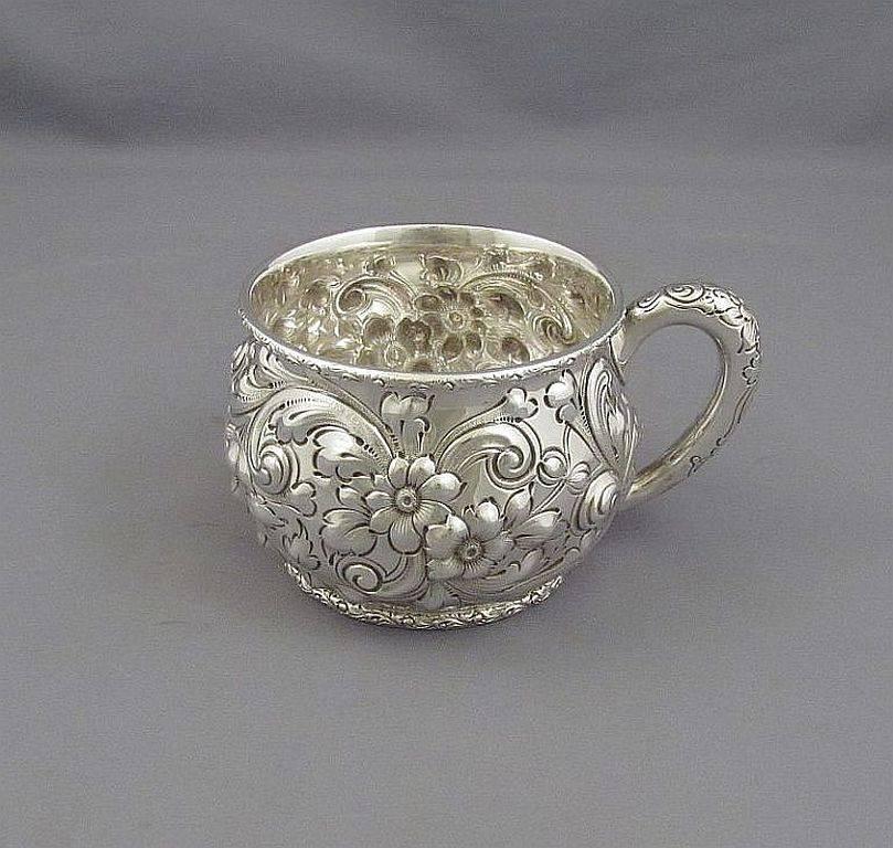 A fine quality antique sterling silver mug by Dominick & Haff, New York, circa 1888. Fine repoussé flowers scrolls and foliage with convex sides, retailed by Theodore B Starr. Measures: 4