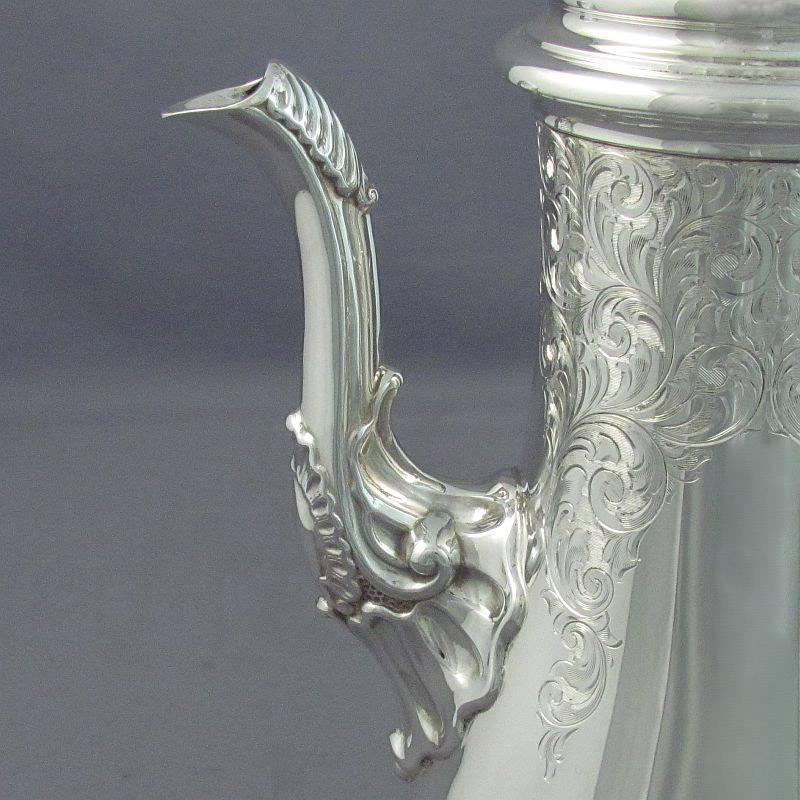 A large George II style sterling silver coffee pot by Henry Birks & Sons, Montreal 1963. Baluster shape with scroll handle and spout, hand engraved with scrolls and foliage. Measures: 11