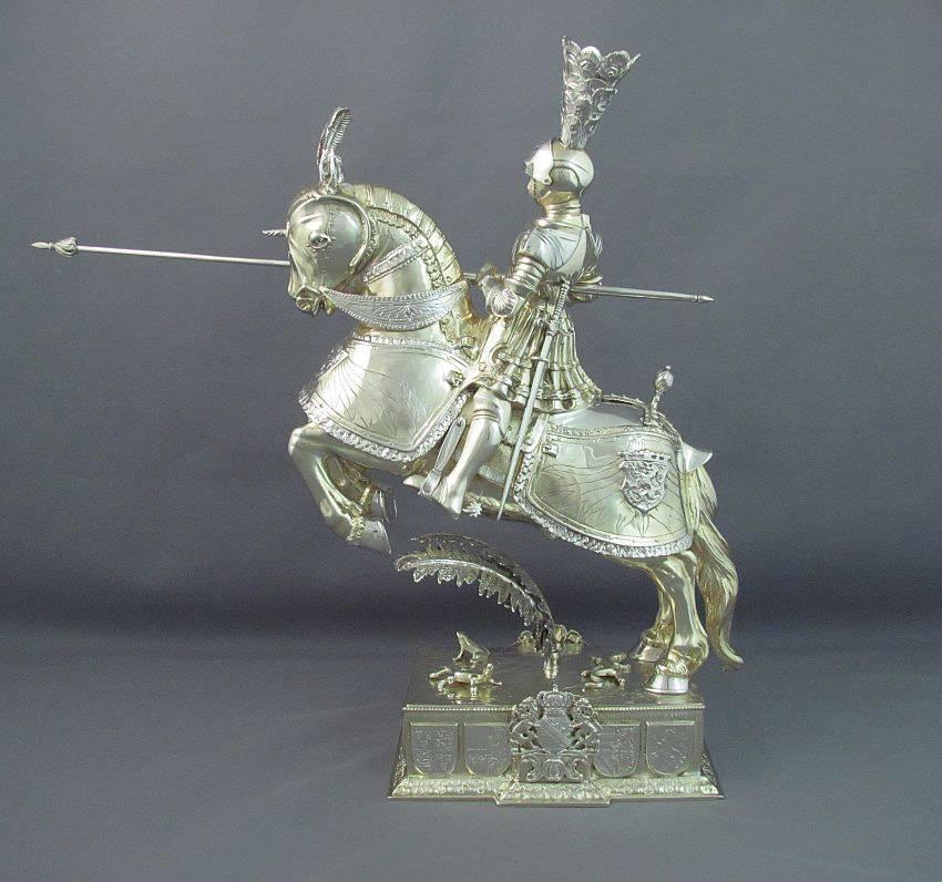 A pair of German silver knights on horseback by Neresheimer & Co., Hanau c. 1895.  Realistically modeled as knights in armour with swords and lances, astride galloping horses in a jousting pose, parcel gilt with carved ivory faces, the rectangular