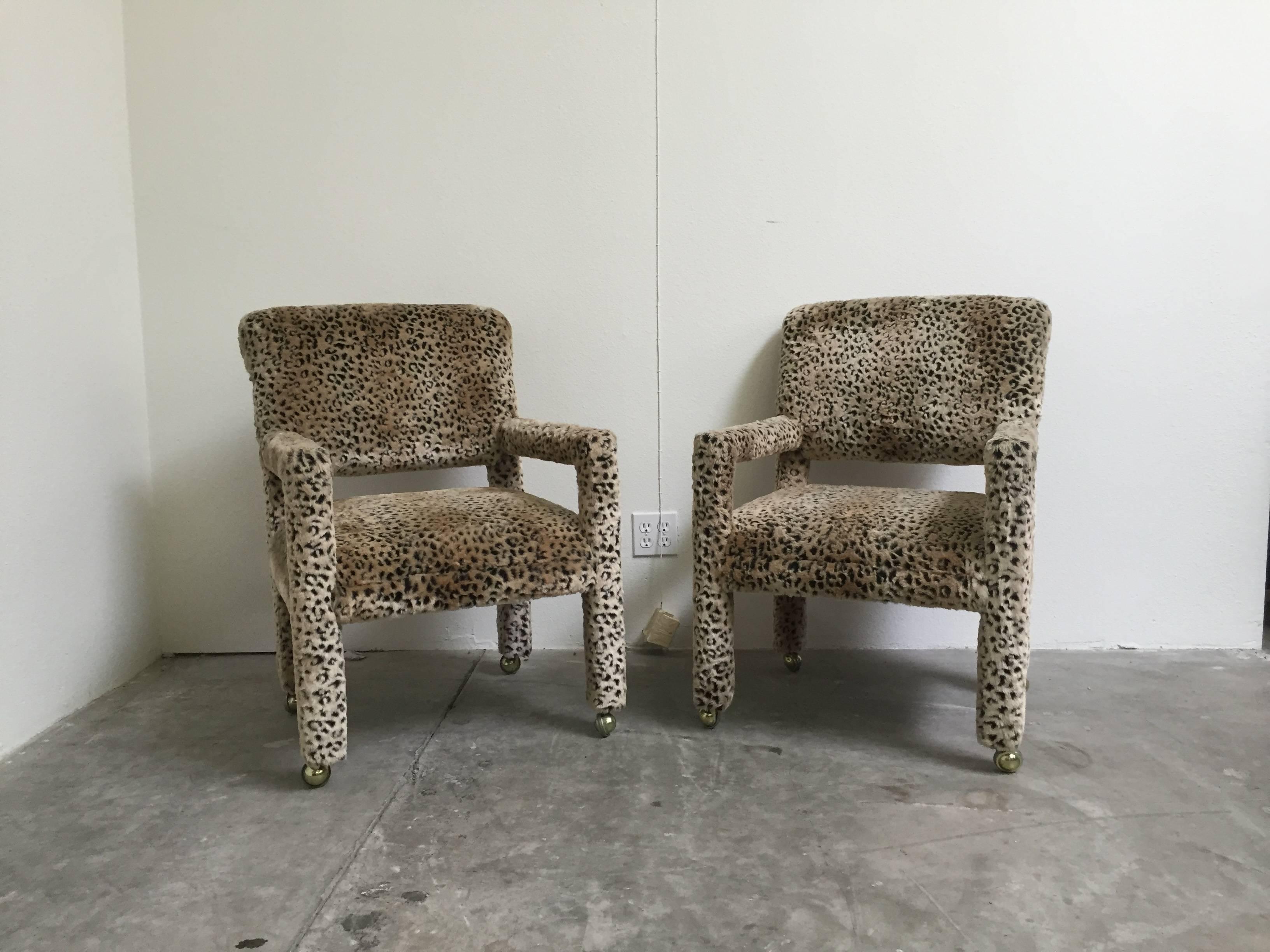 Pair of 1970s Leopard Parson chairs in the style of Milo Baughman. On gold casters with rolled backs. These statement pieces would work as occasional chairs, dining chairs, side chairs or desk chairs. All original material in outstanding vintage