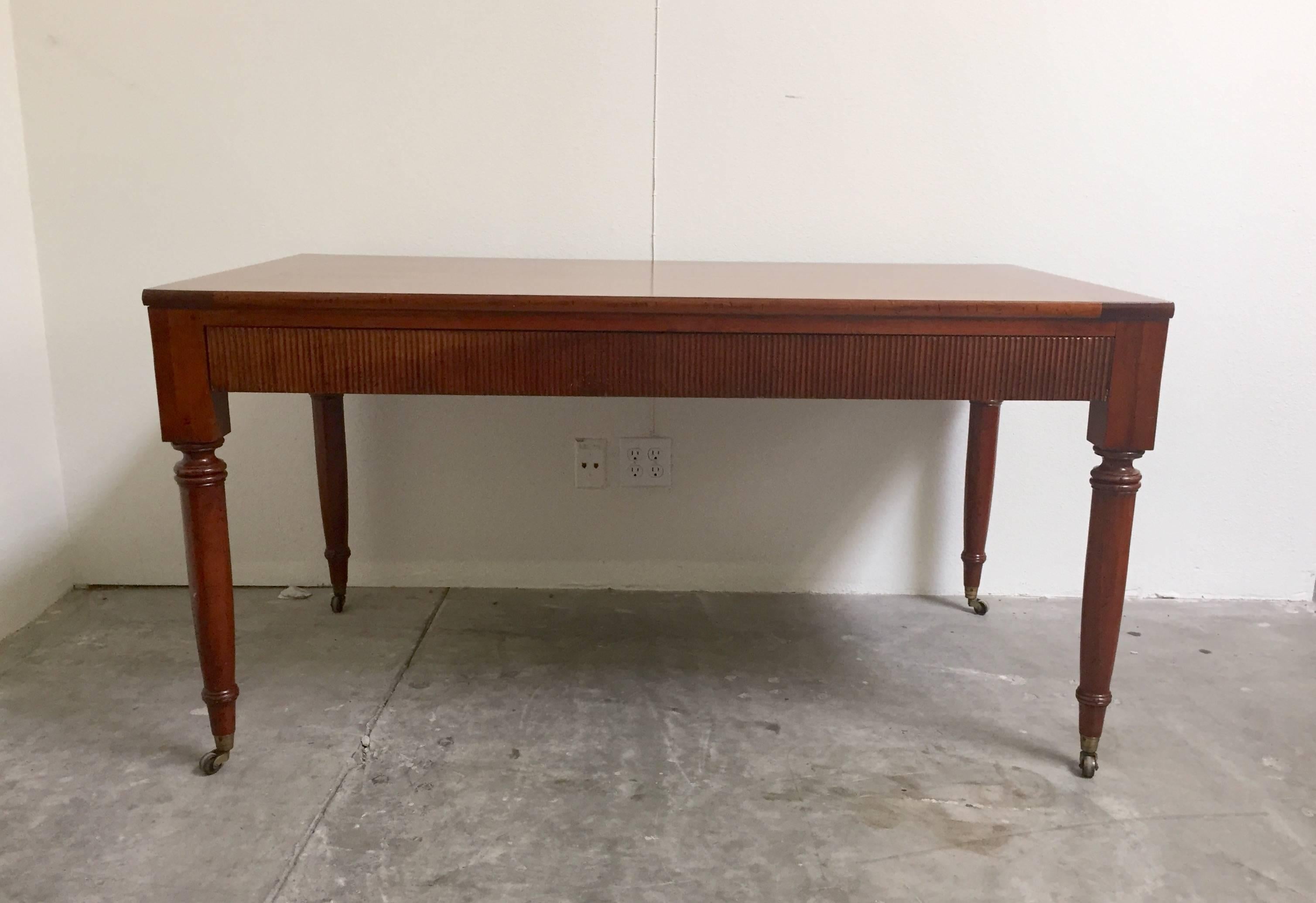 Regency style milling road by baker floating desk. Oversized drawer on one side, brass casters and detailing around the edges and on the legs. Makers mark on the left side of the drawer.