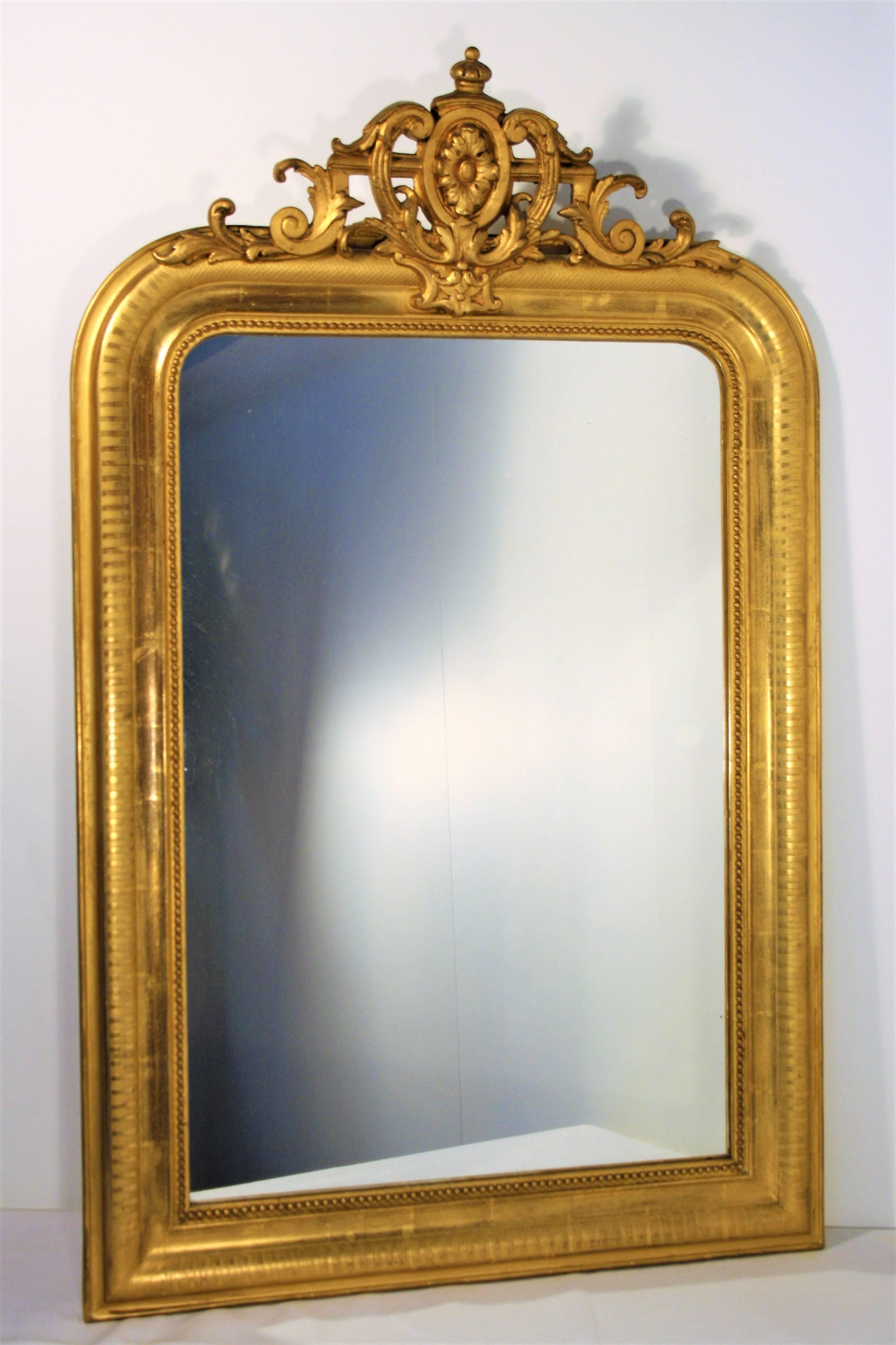 A beautiful French Louis Philippe gold gilt mirror with cartouche from mid-19th century, with its original mercury glass and its original wooden back.