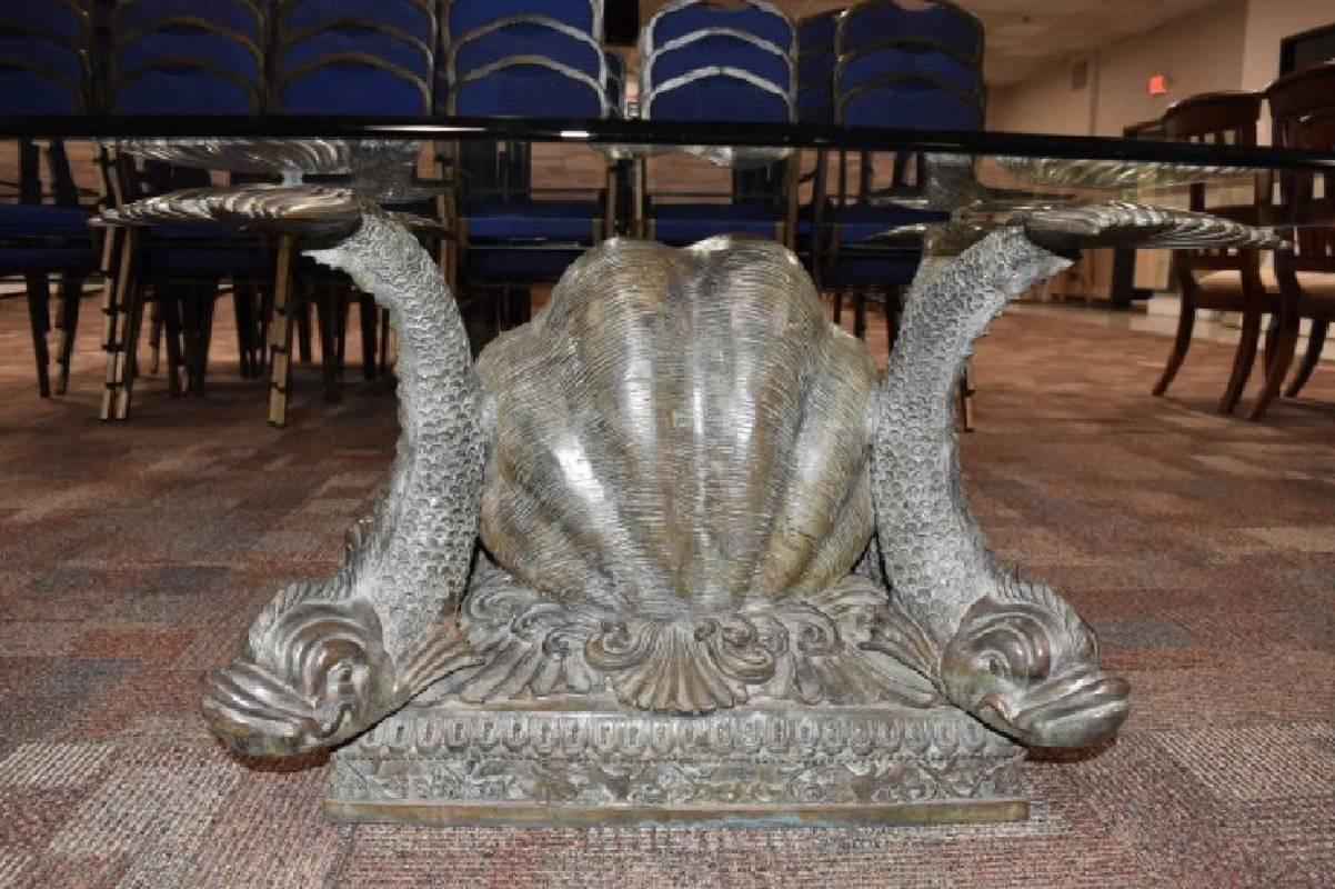 This exquisite bronze coffee table adds a perfect neoclassical touch to any space. The Classic dolphin or koi and shell motifs have been a tradition in furniture making for centuries and this is a handsome example. The piece is shown with a glass