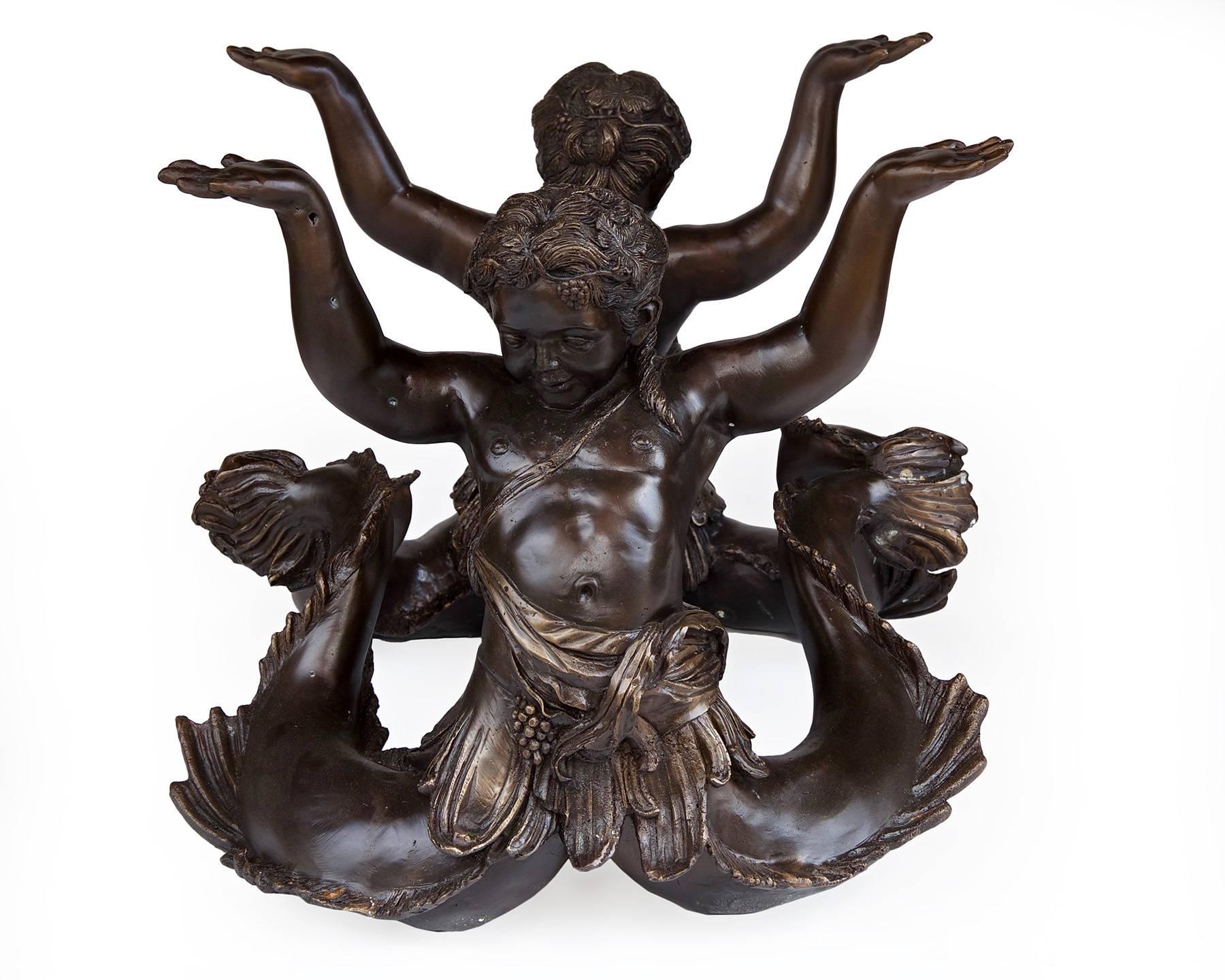 Elegant and unique coffee table of patinated bronze and glass. The bronze base depicts a pair of aquatic cherubs, or mermen the table top above their heads. Beautiful casting and a bronzed patina make this piece a showstopper. Unsigned, but